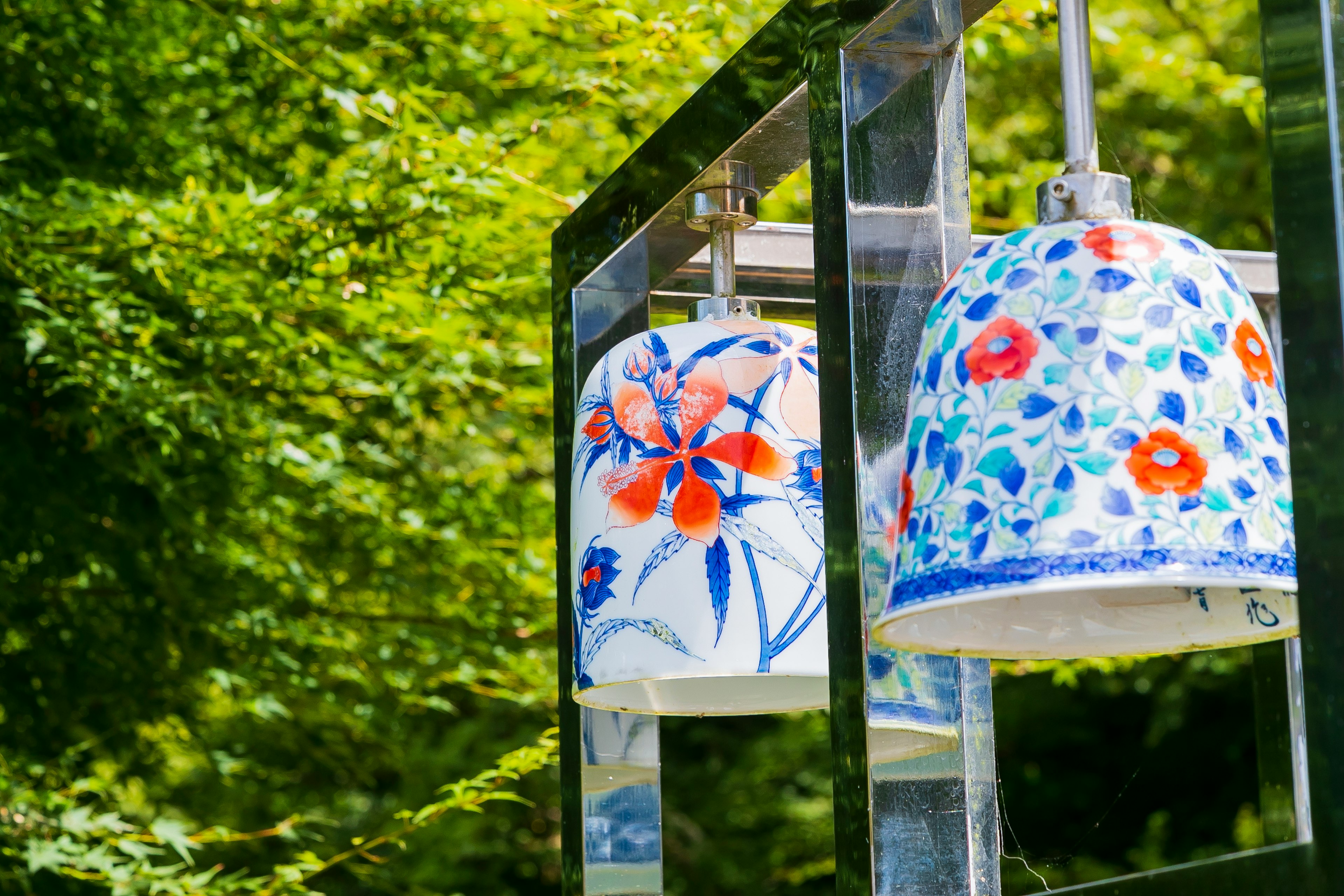 Campanas de viento coloridas con diseños florales colgando sobre un fondo verde