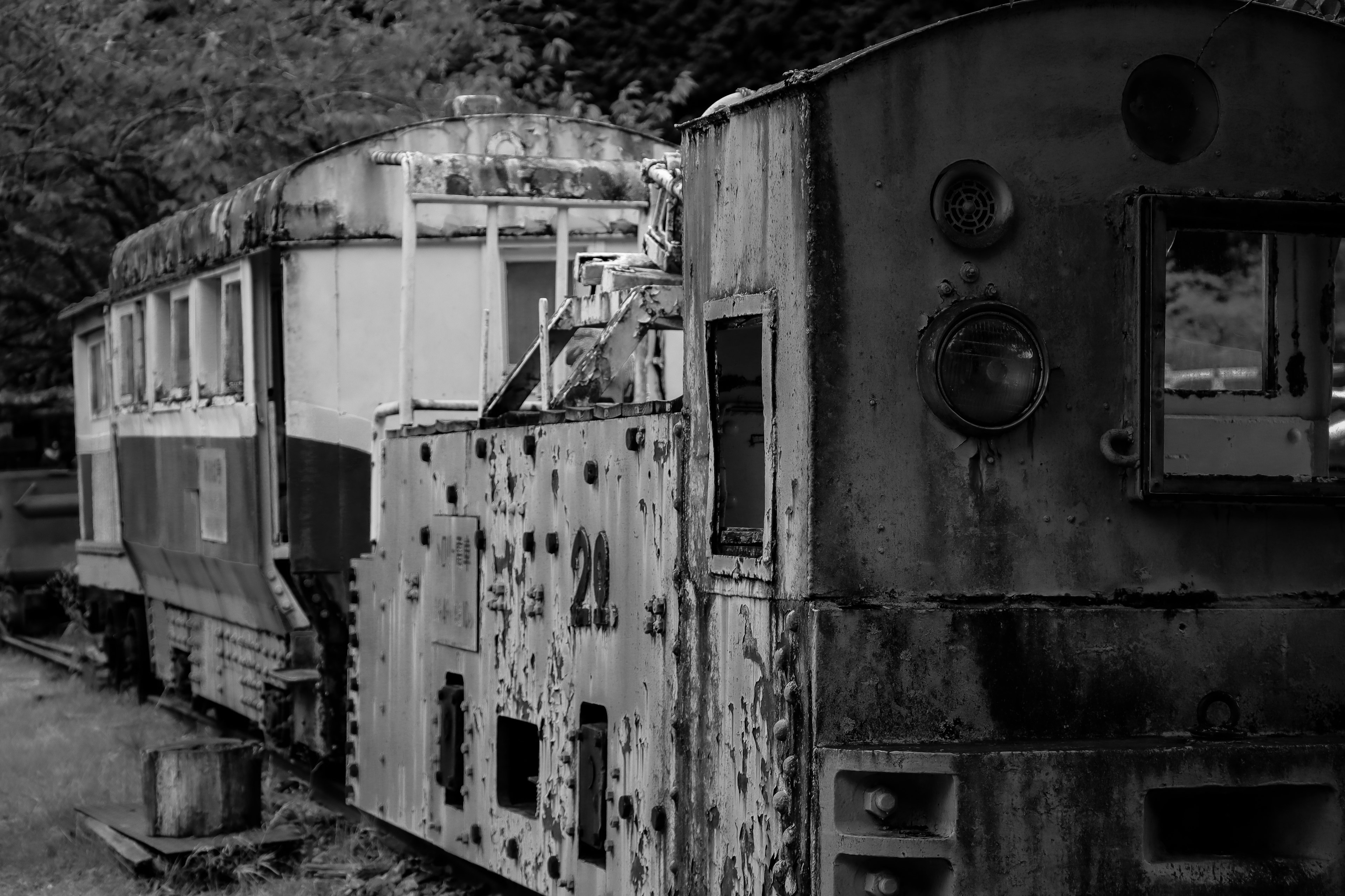 Old steam locomotive and passenger car in a rustic setting featuring rusted metal and faded paint