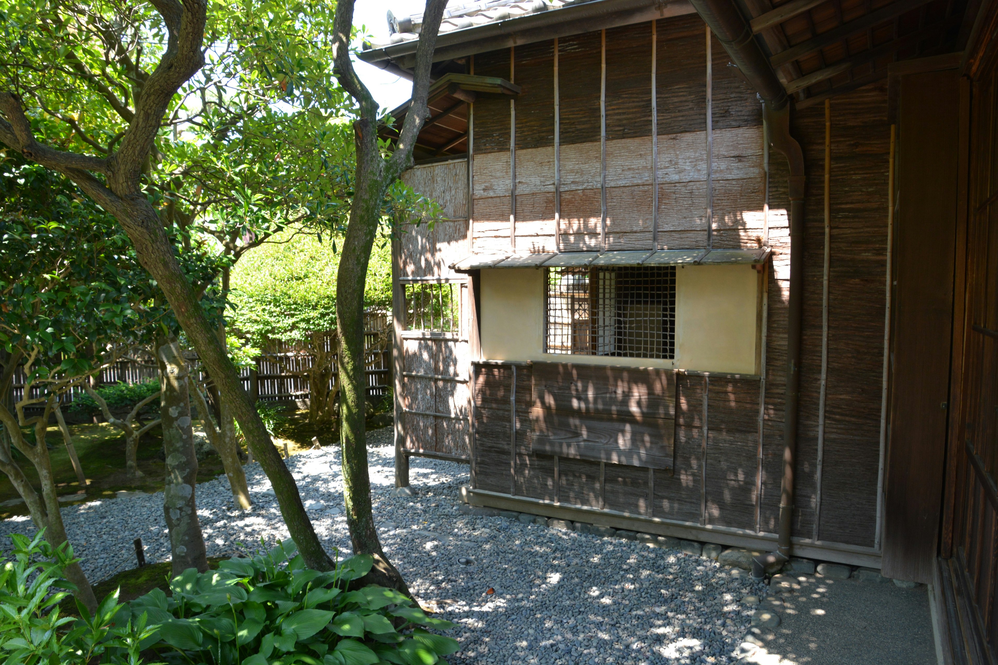 Traditional wooden house with a garden view featuring green plants and a stone path