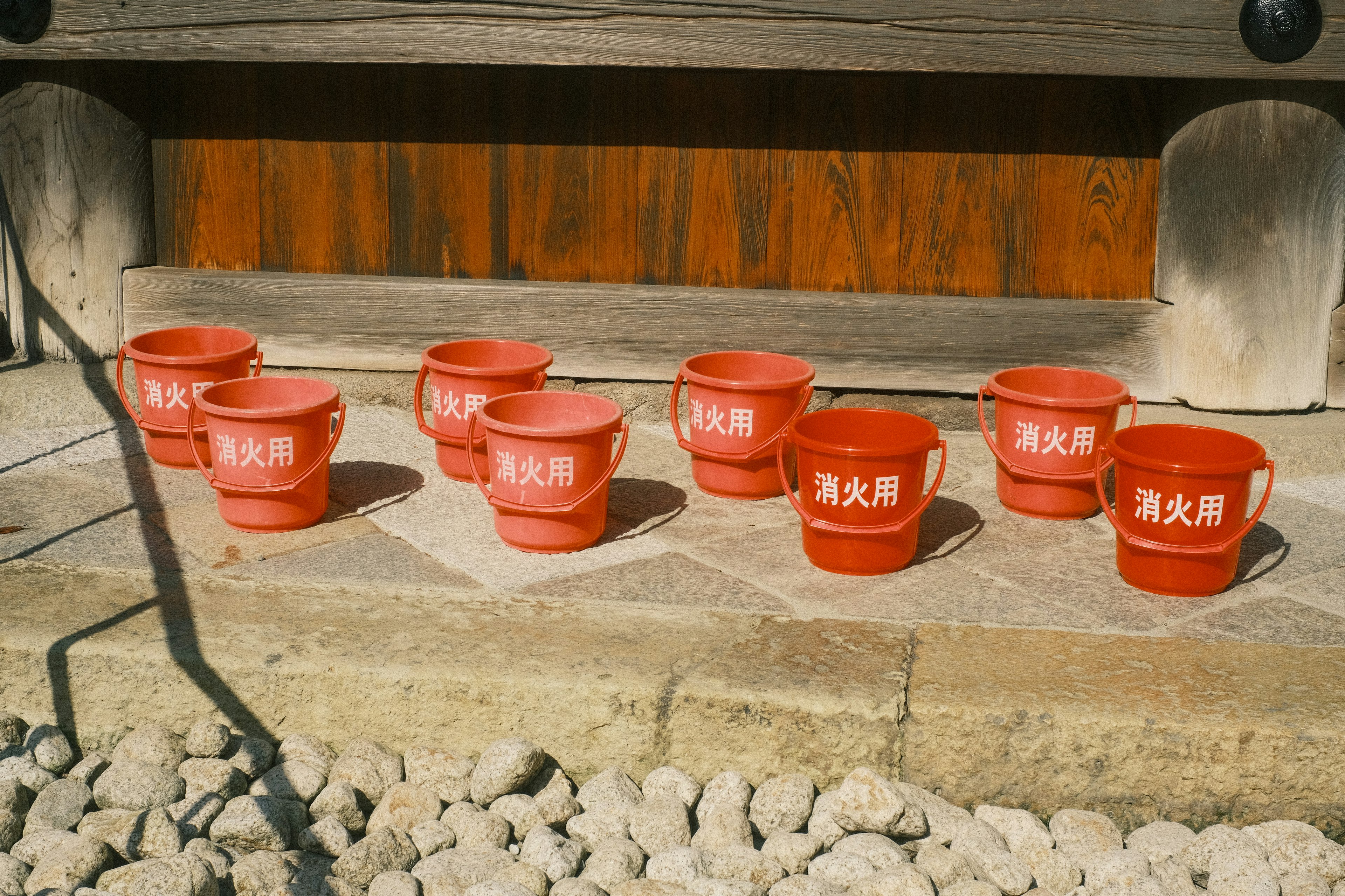 Rangée de pots rouges avec des caractères japonais sur une surface en pierre