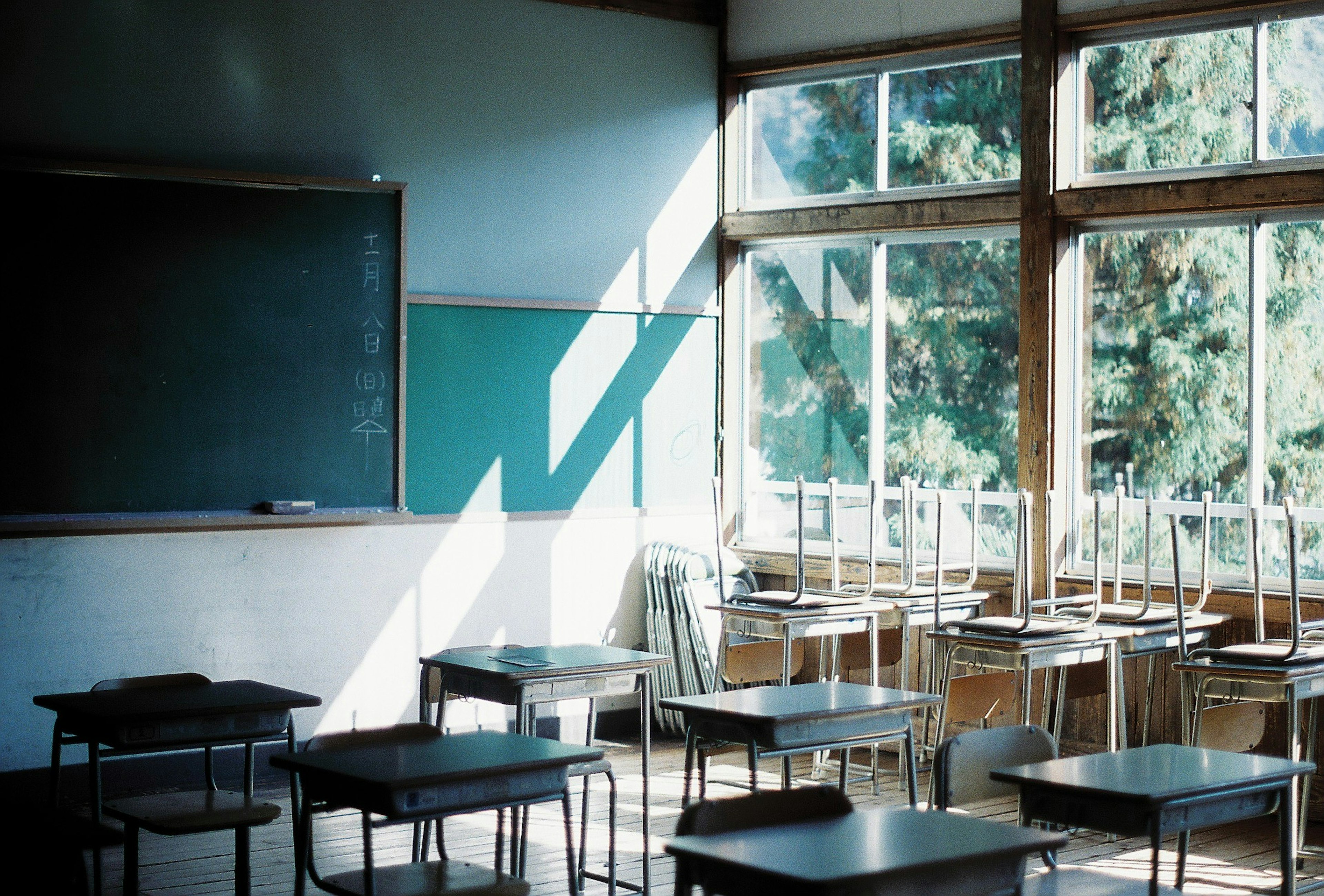 Interior de un aula con escritorios y sillas dispuestos luz natural que entra por las ventanas