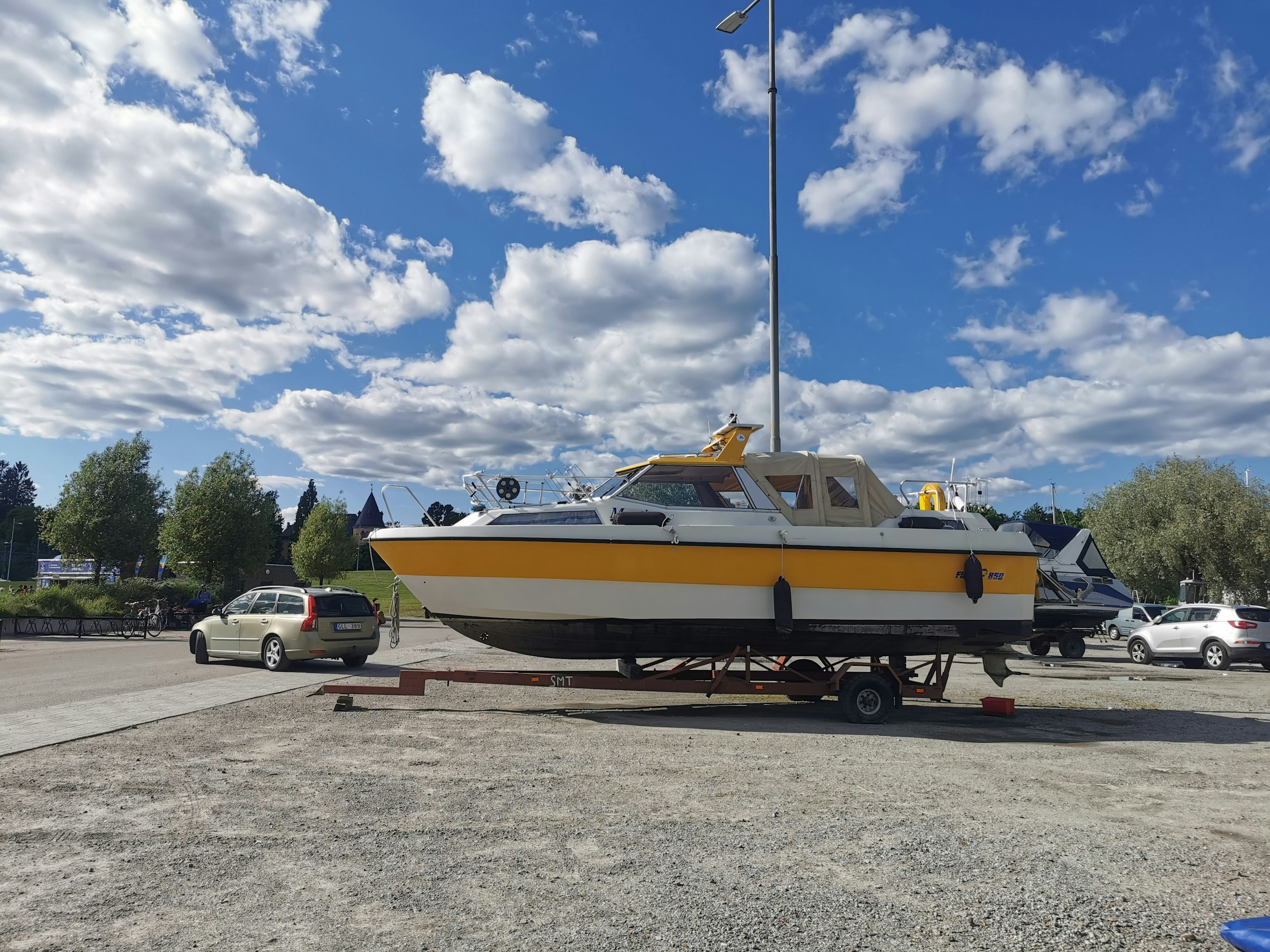 A yellow boat on a trailer in a parking lot