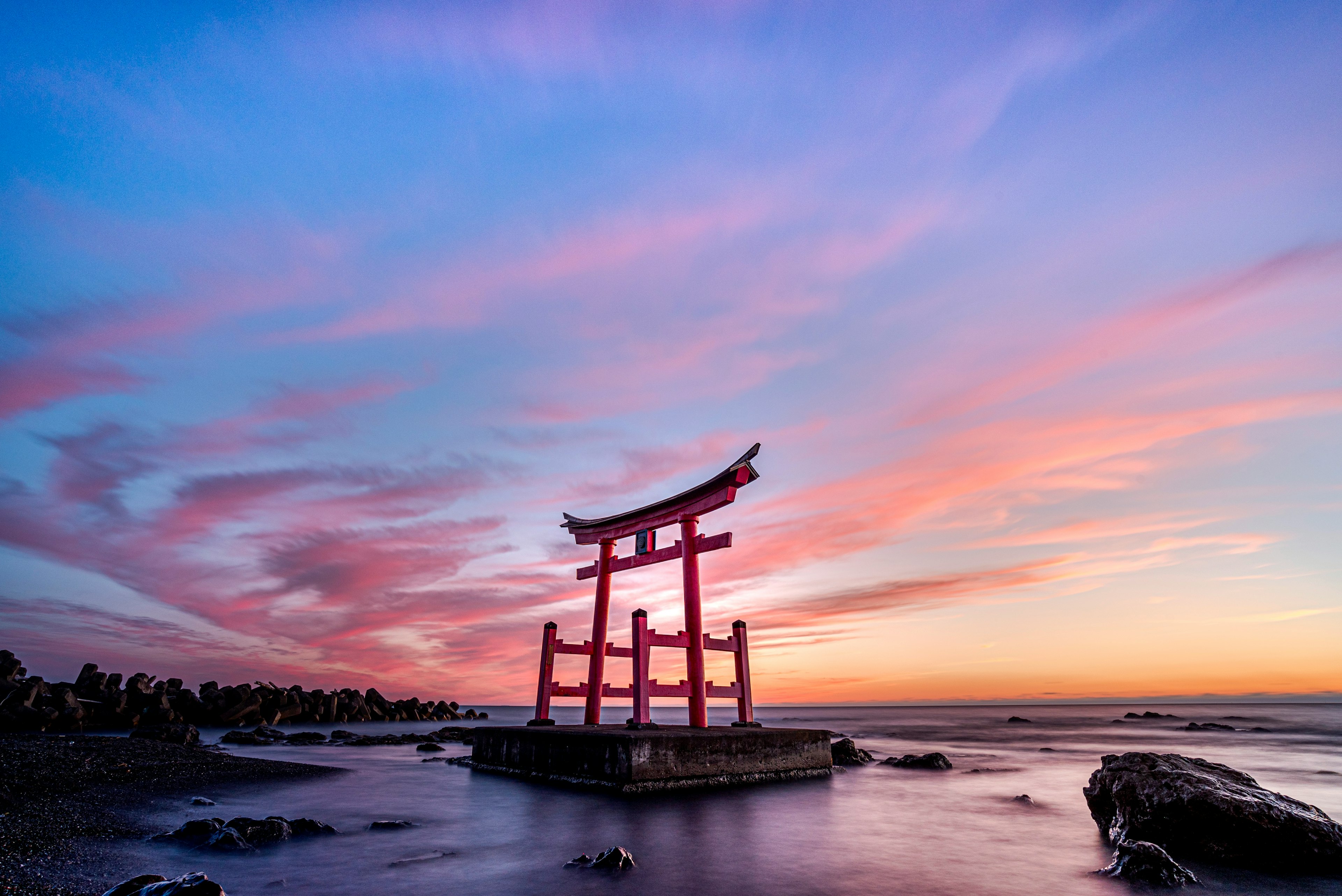 美しい夕焼けの中に立つ赤い鳥居と海の風景