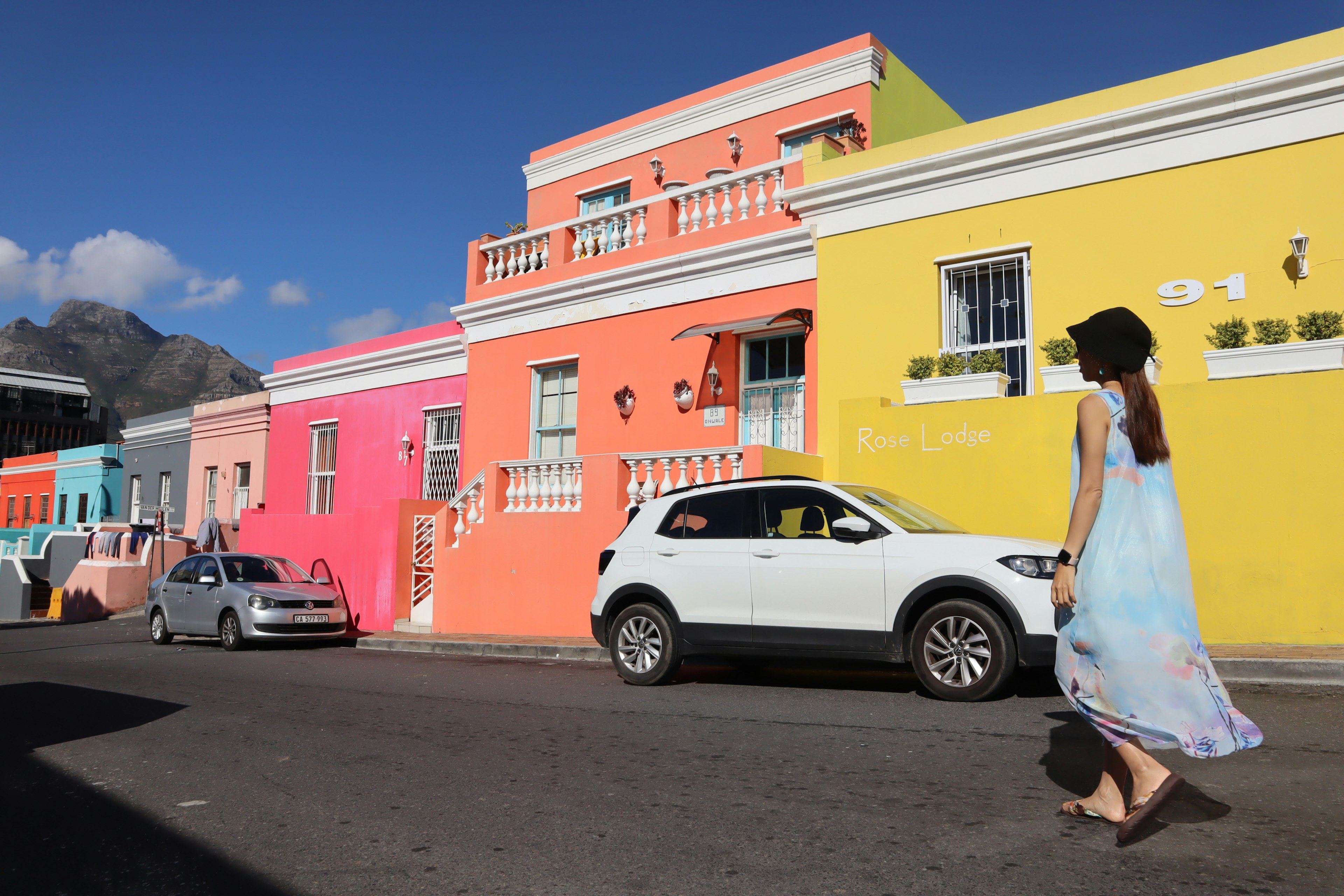 A woman walking on a street with colorful houses