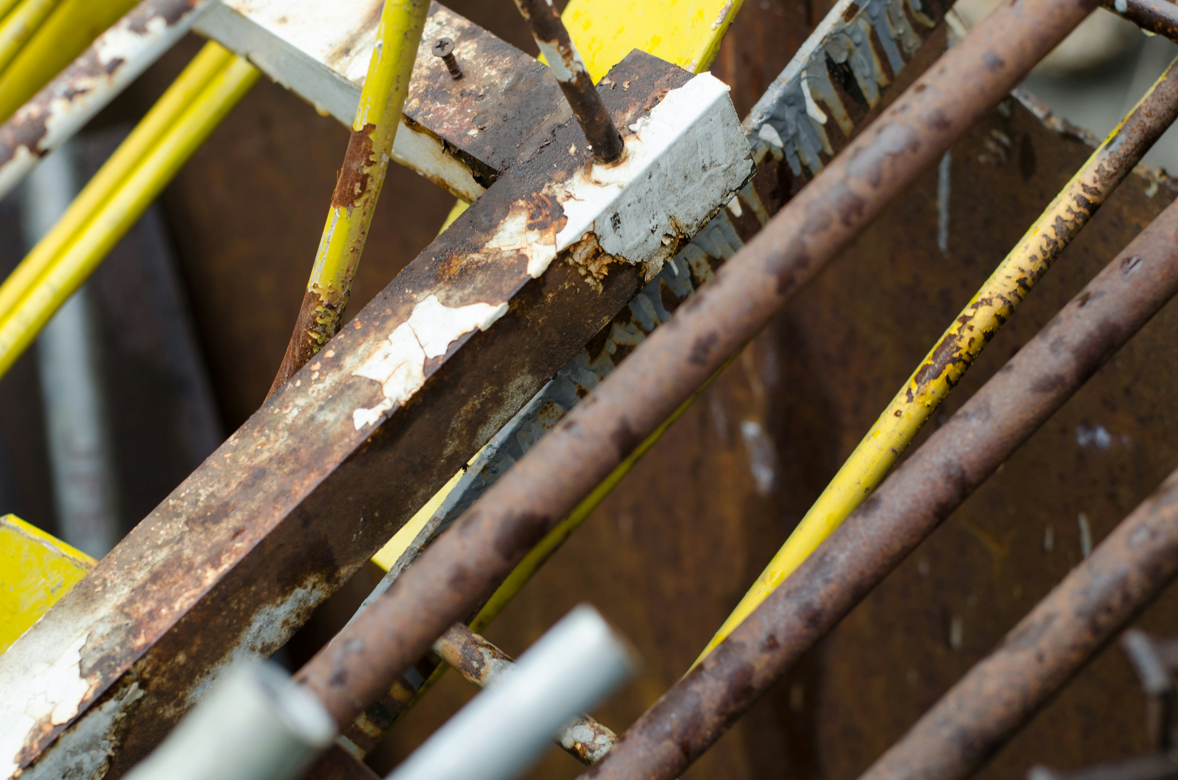 Close-up of a structure featuring yellow pipes and rusted metal