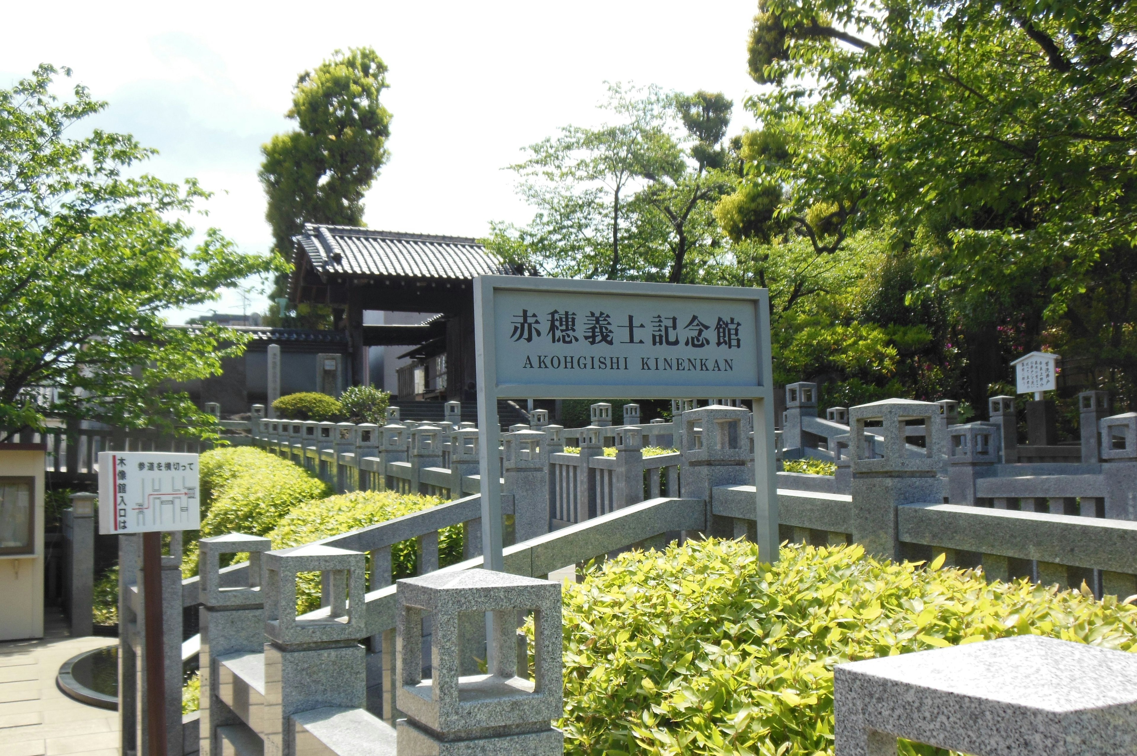 緑豊かな景色の中にある記念館の看板と石の手すり