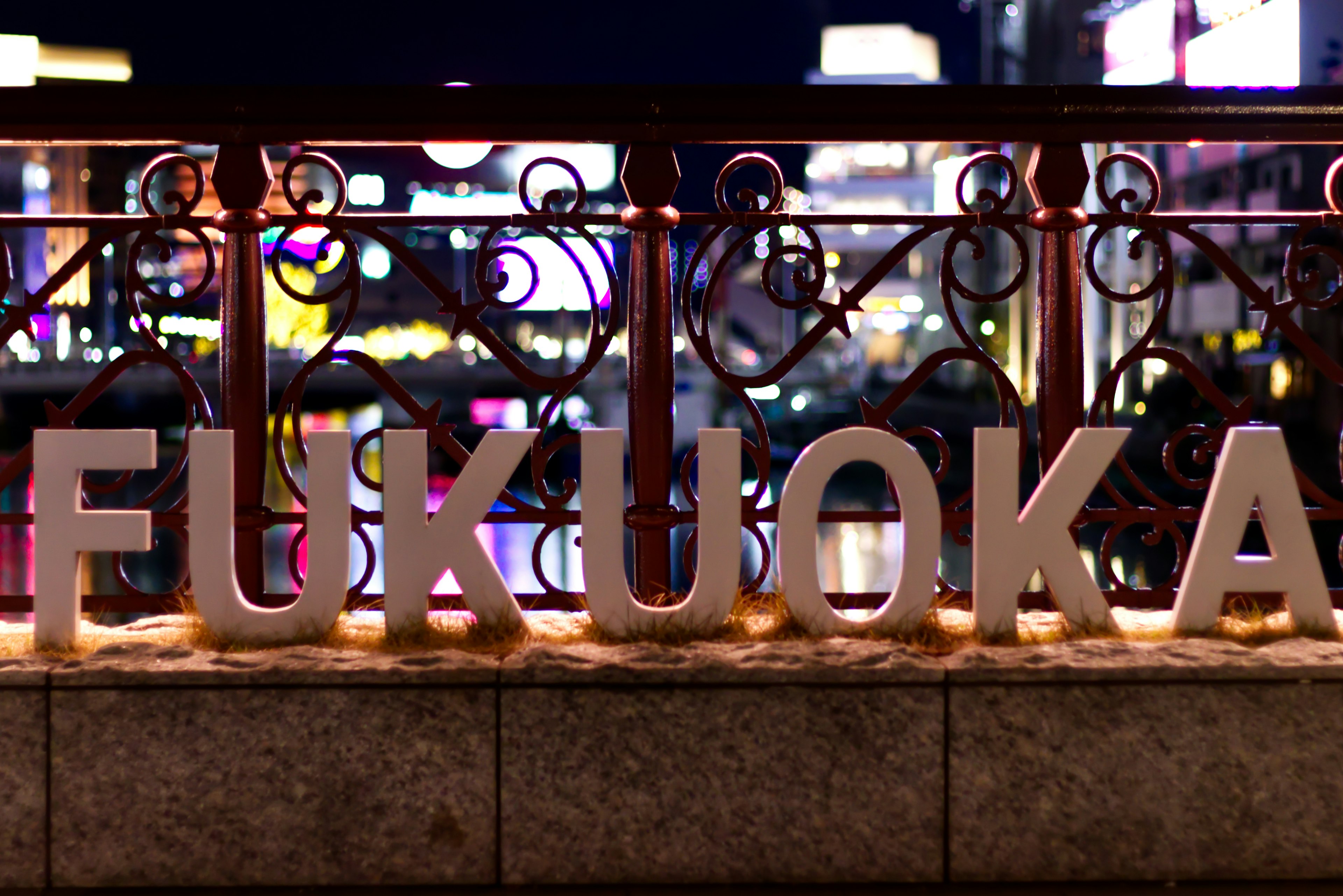 Illuminated Fukuoka sign along the riverside at night