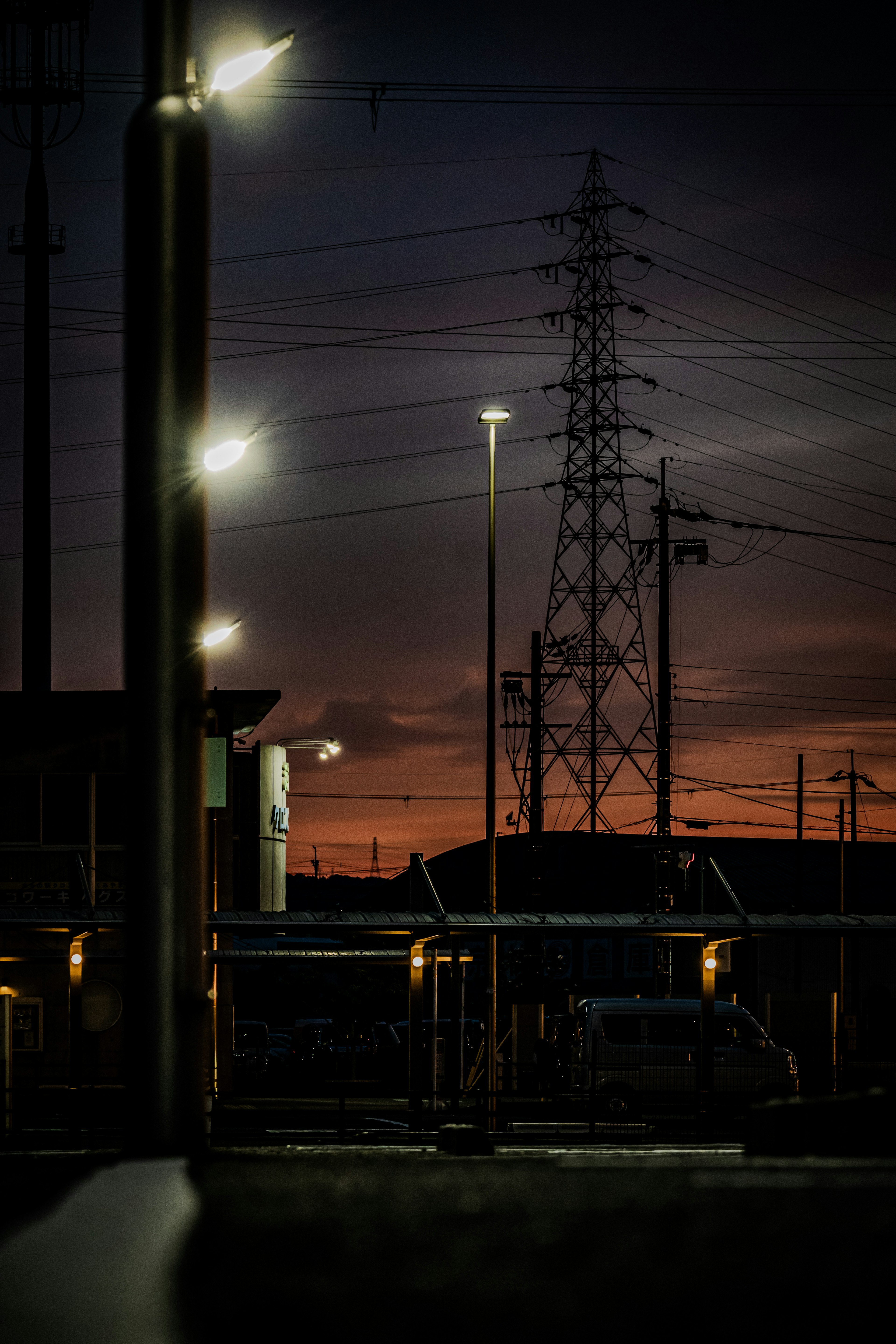 Un paisaje con farolas y líneas eléctricas al atardecer