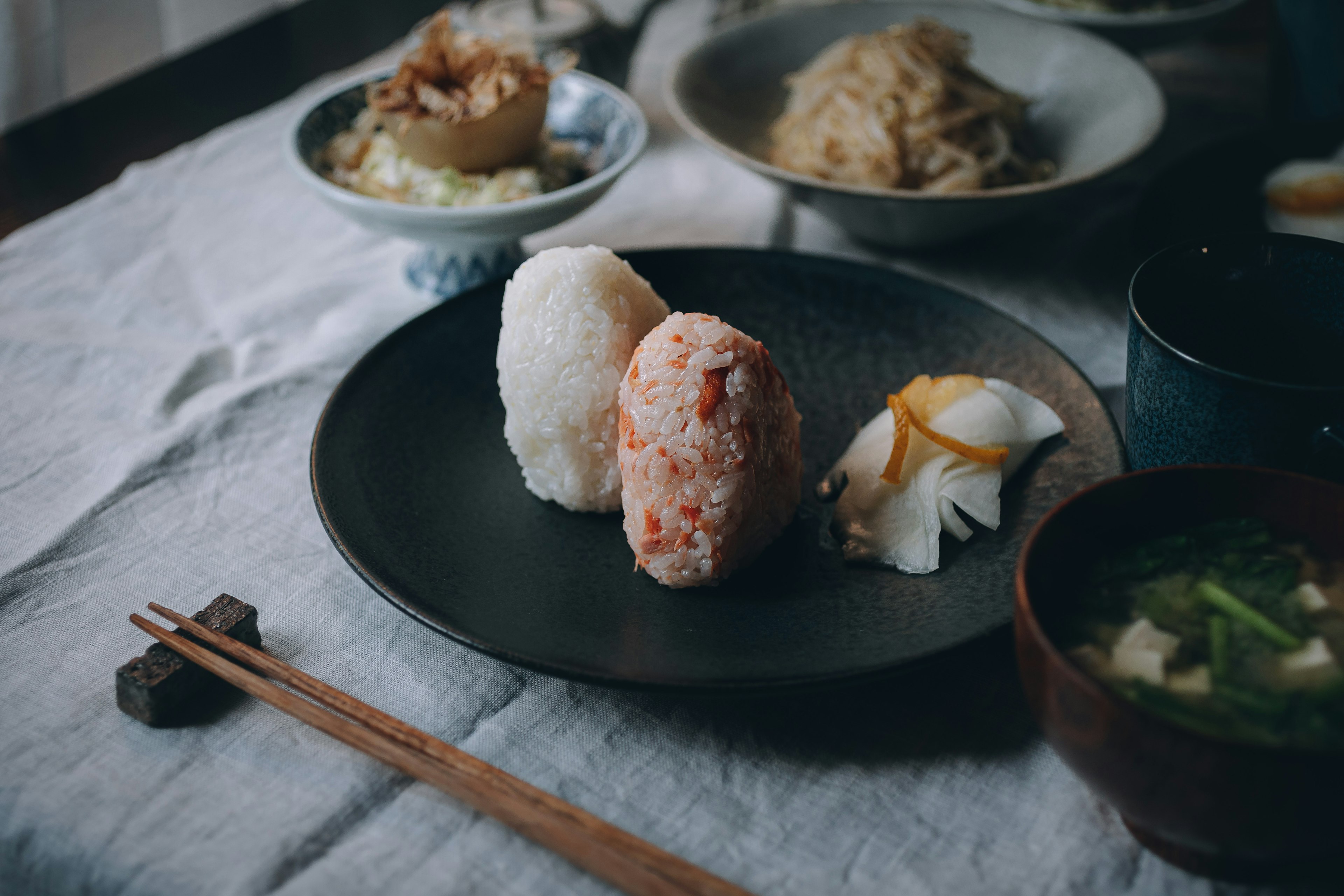 Rice balls on a black plate with various side dishes