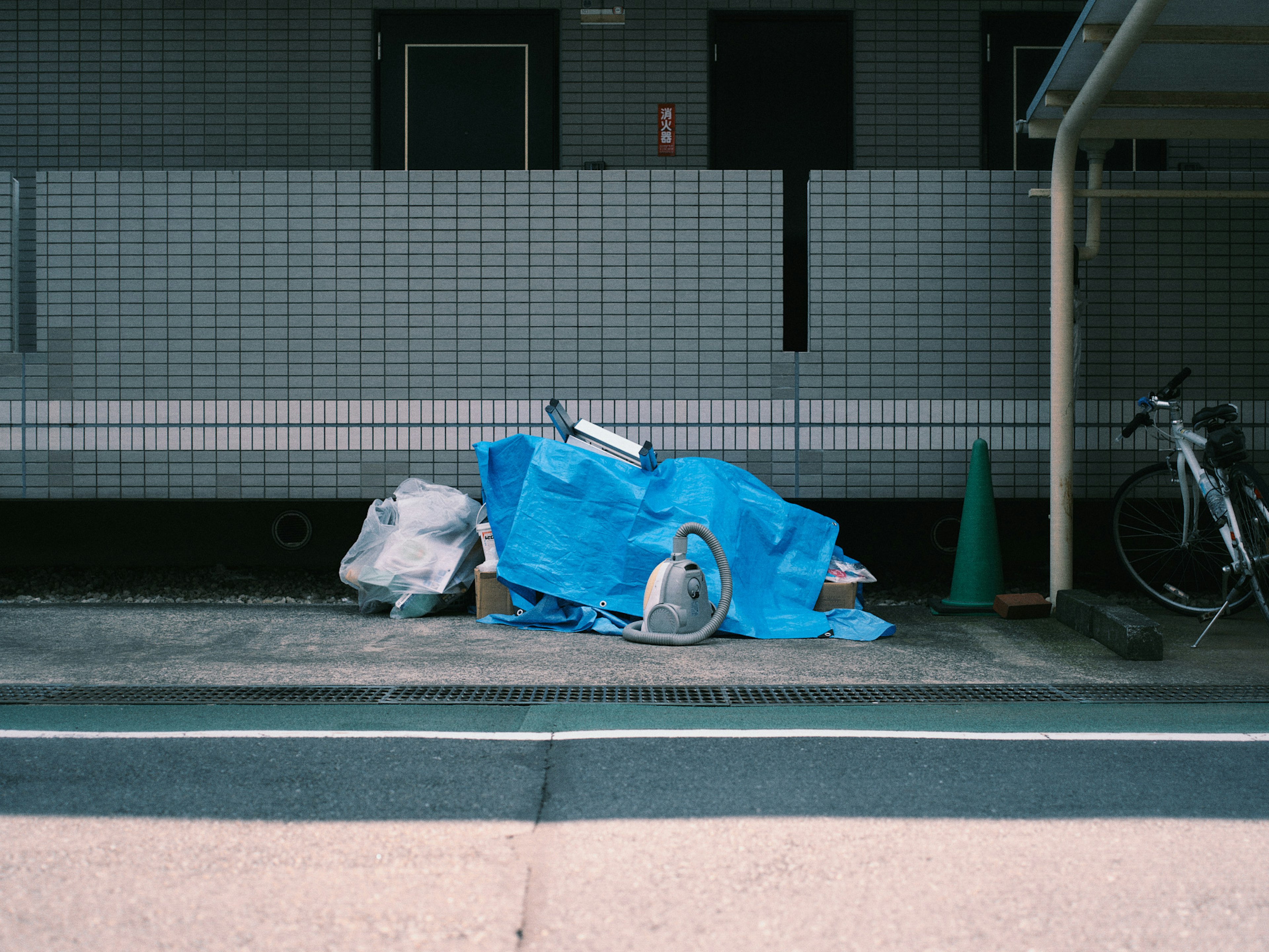 A pile of trash covered with a blue tarp next to a bicycle