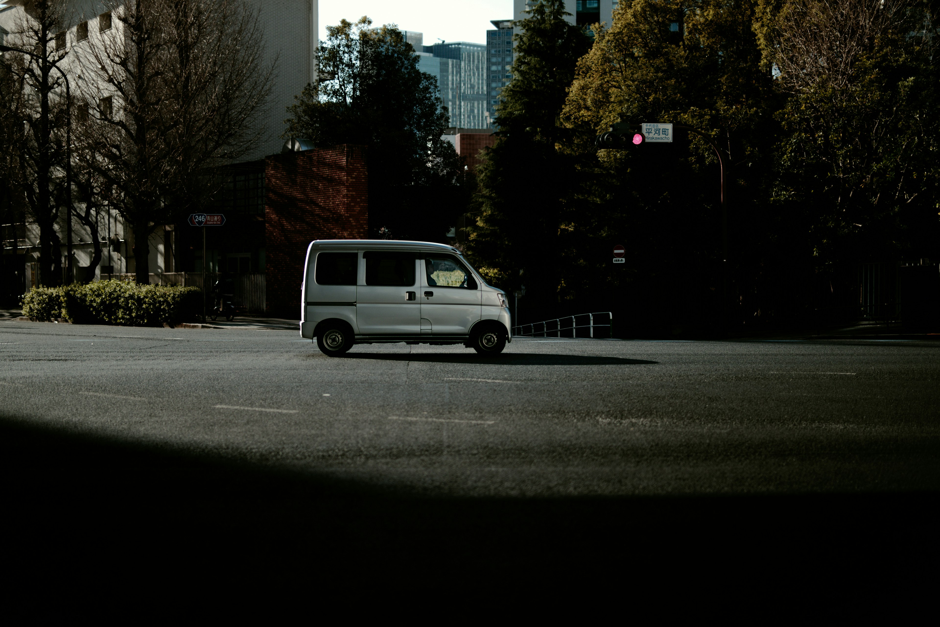 A white van driving at an intersection in an urban setting