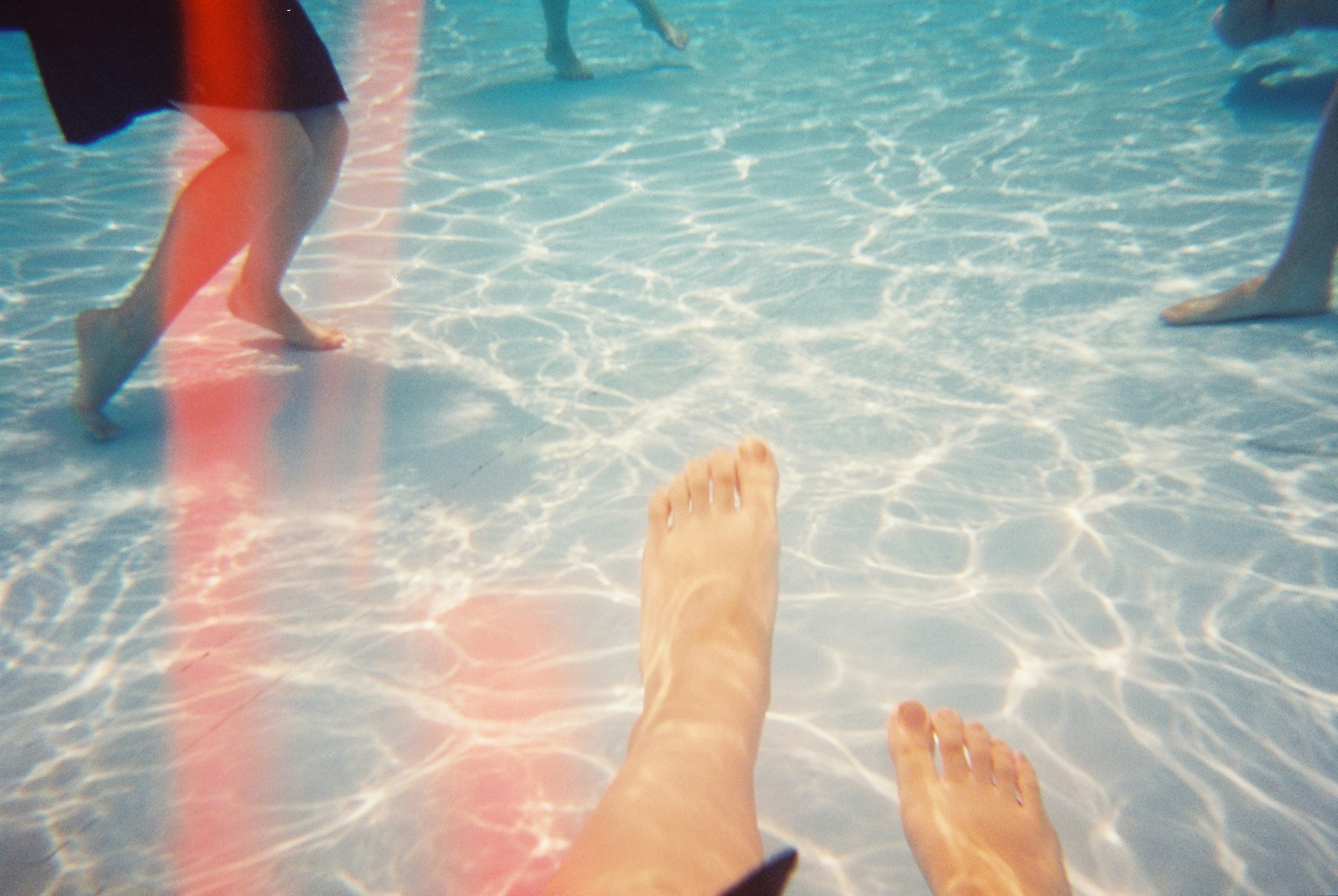 Photo de pieds immergés dans de l'eau claire avec des reflets