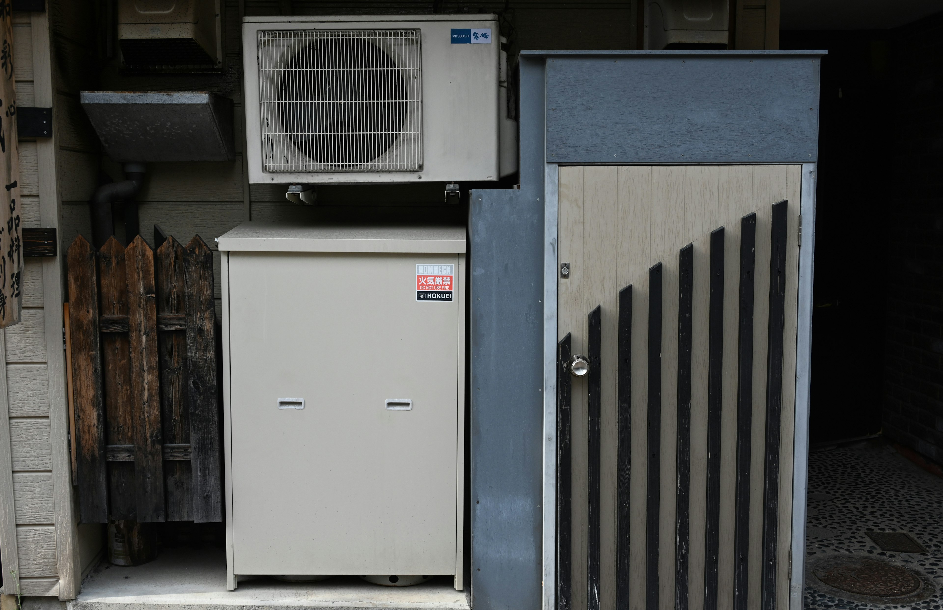 Exterior wall section featuring an air conditioning unit and storage box