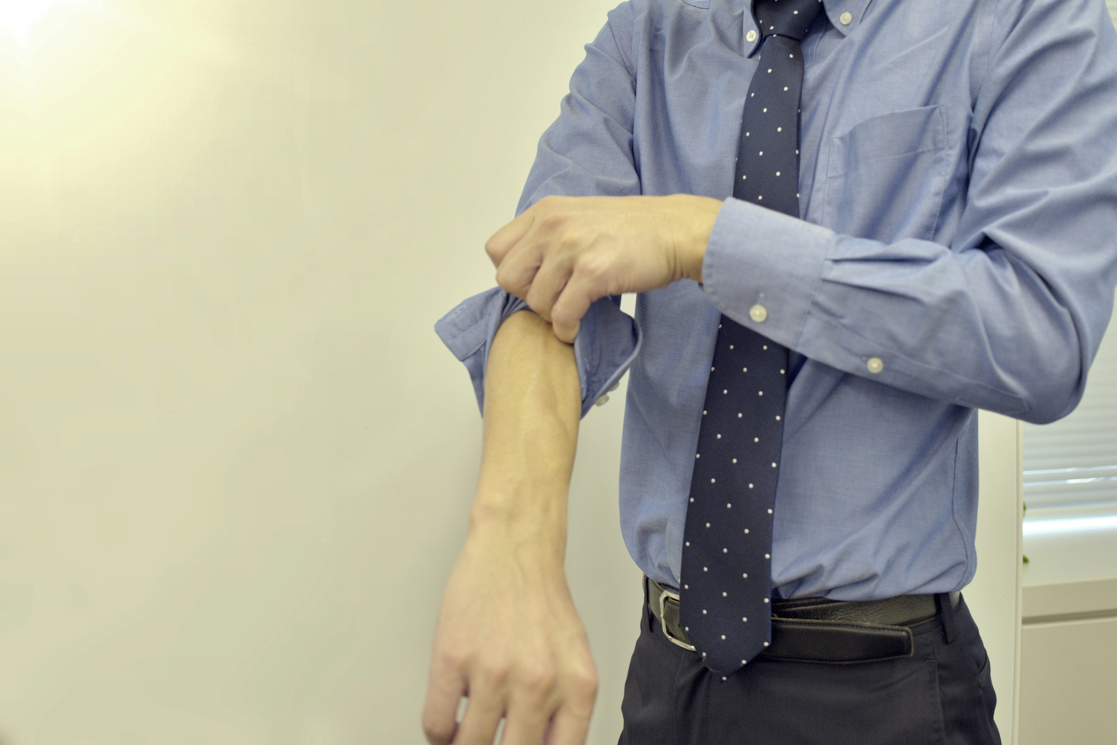 Man rolling up the sleeve of a blue shirt