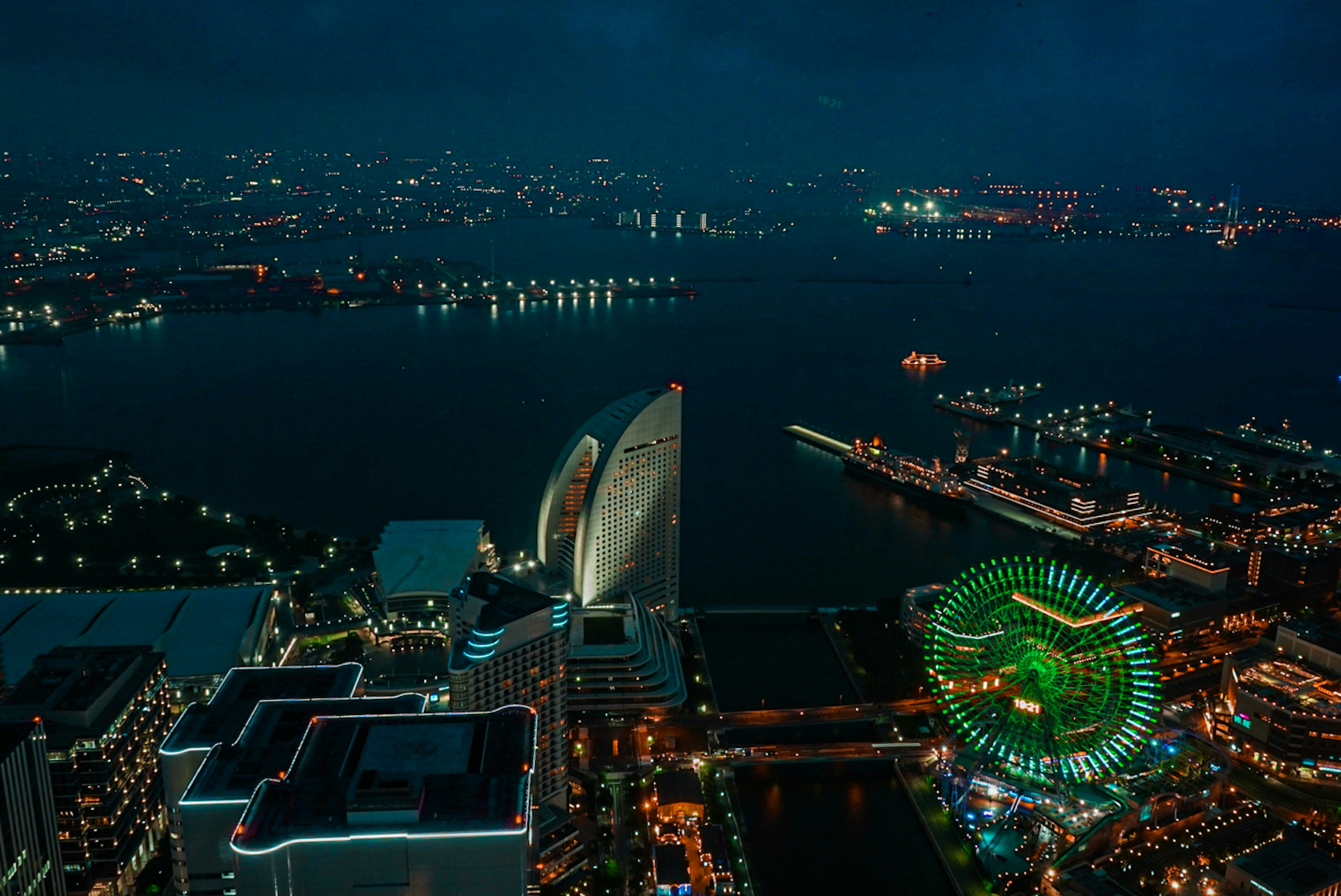 Vue aérienne de Yokohama la nuit avec une grande roue verte et la mer