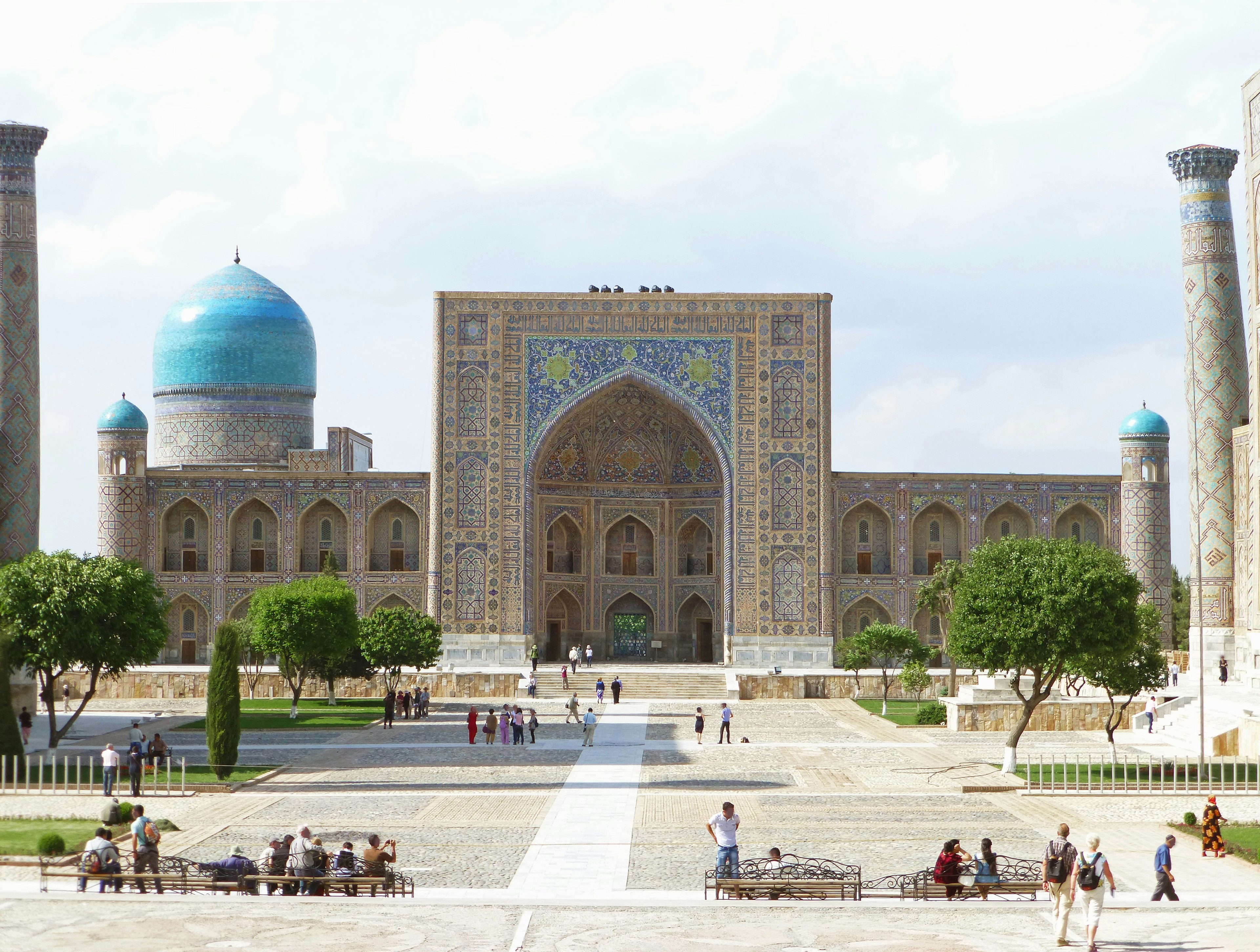 Une grande mosquée avec un dôme bleu se dresse dans une grande place