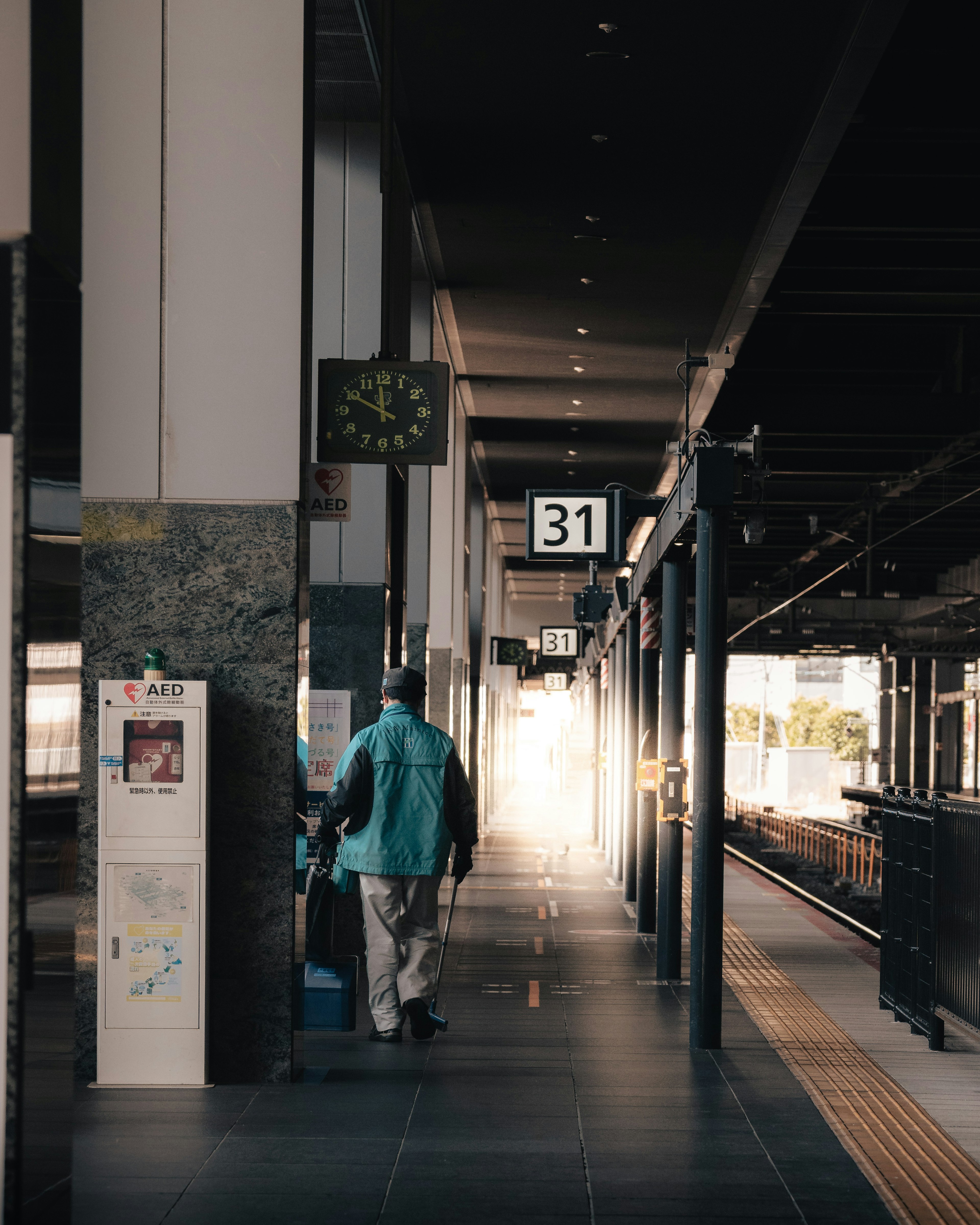 A view of a train station platform with a person and a clock