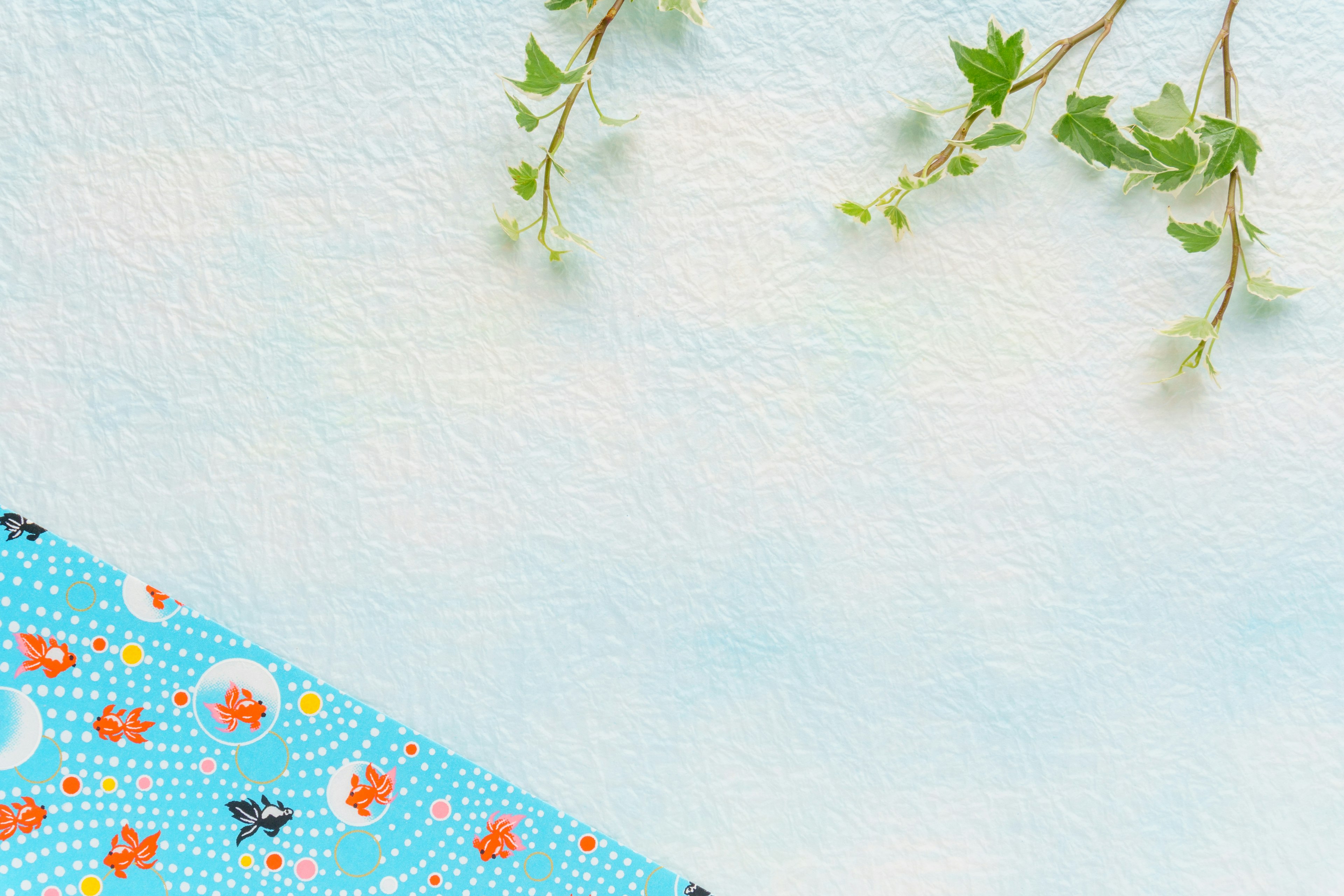 A scene with a blue background featuring vibrant patterned fabric and green leaves