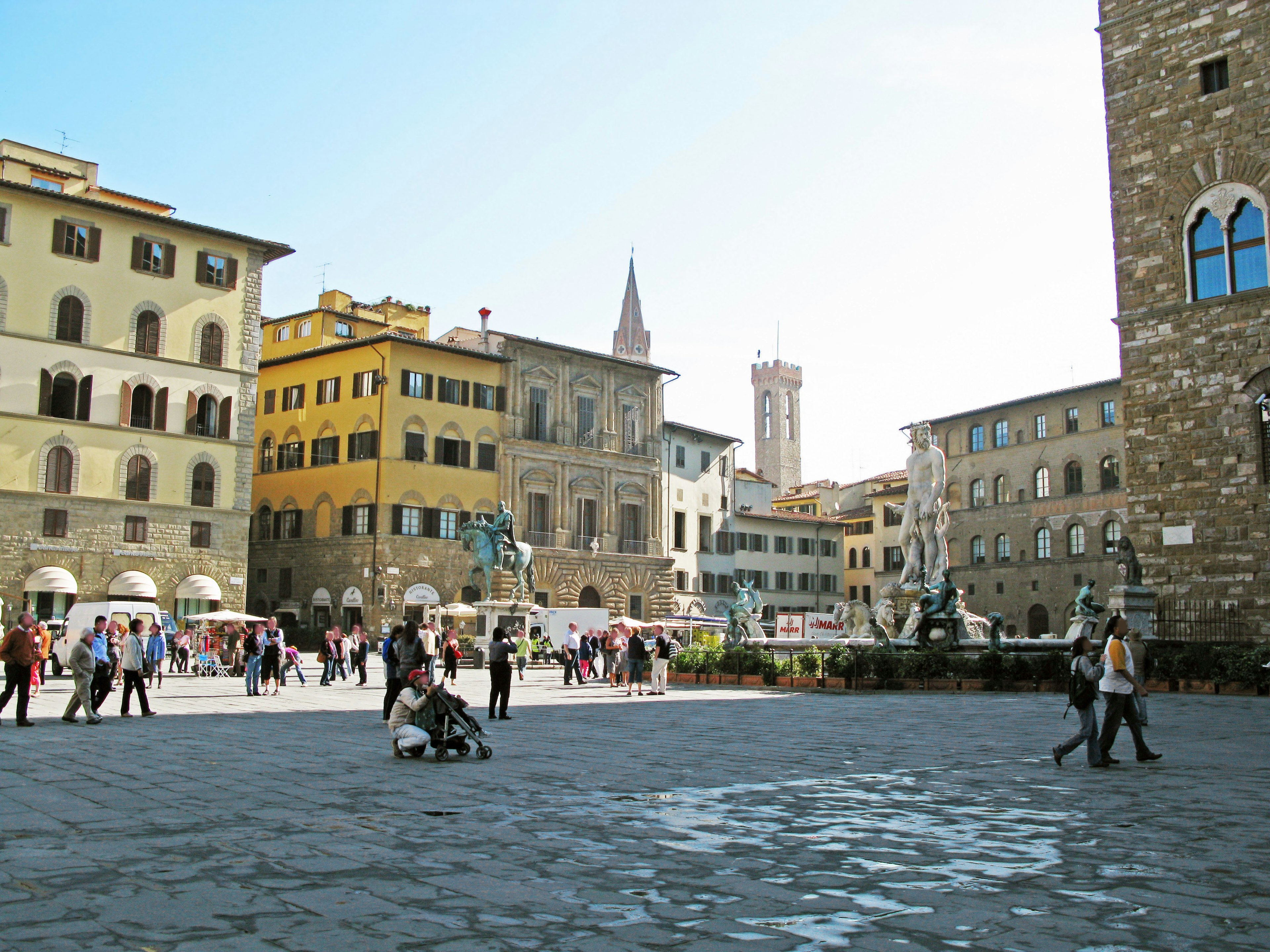 People gathering in a square in Florence featuring stone buildings and a fountain