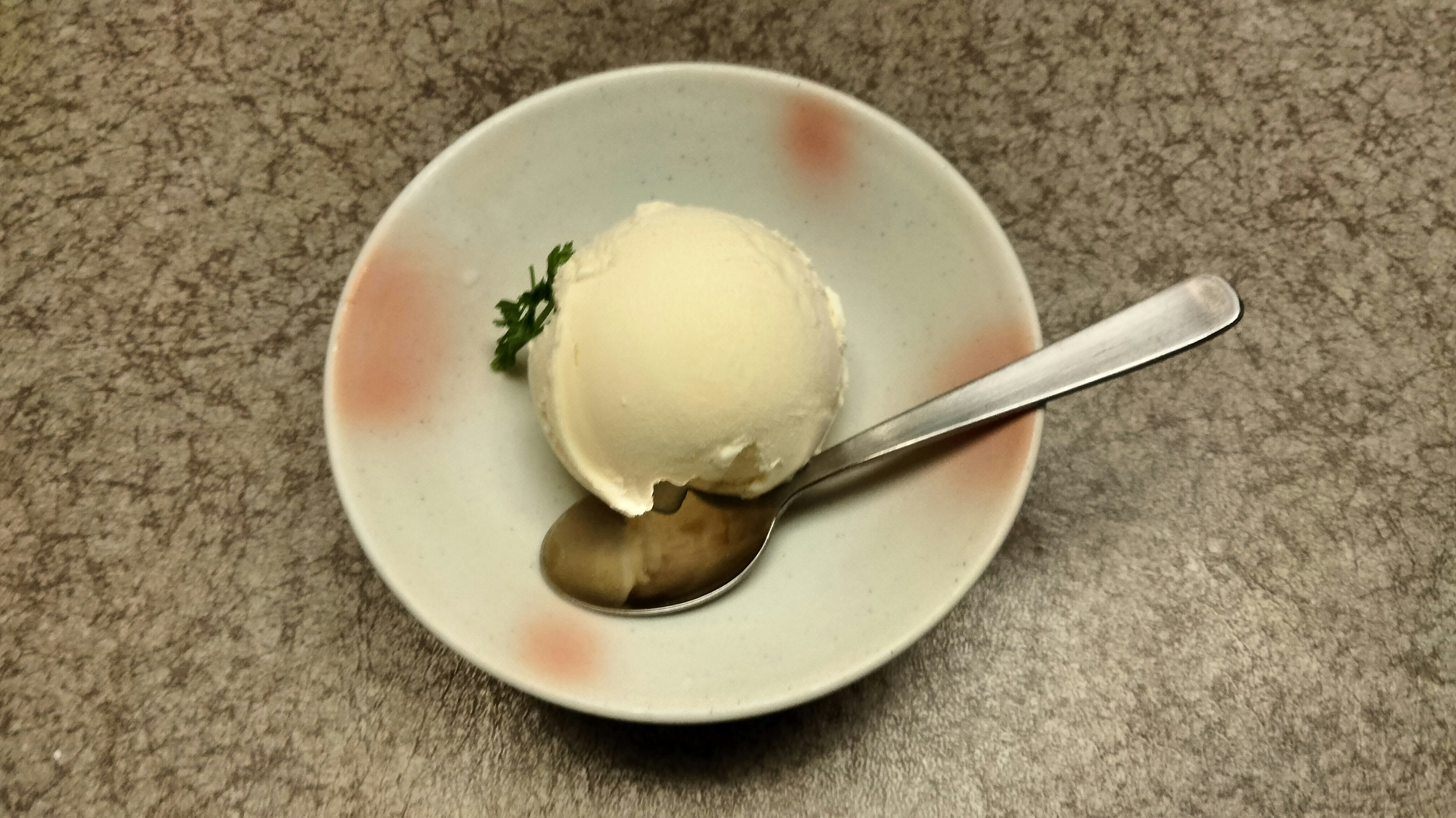 Un pequeño tazón con una bola de helado blanco y una cuchara