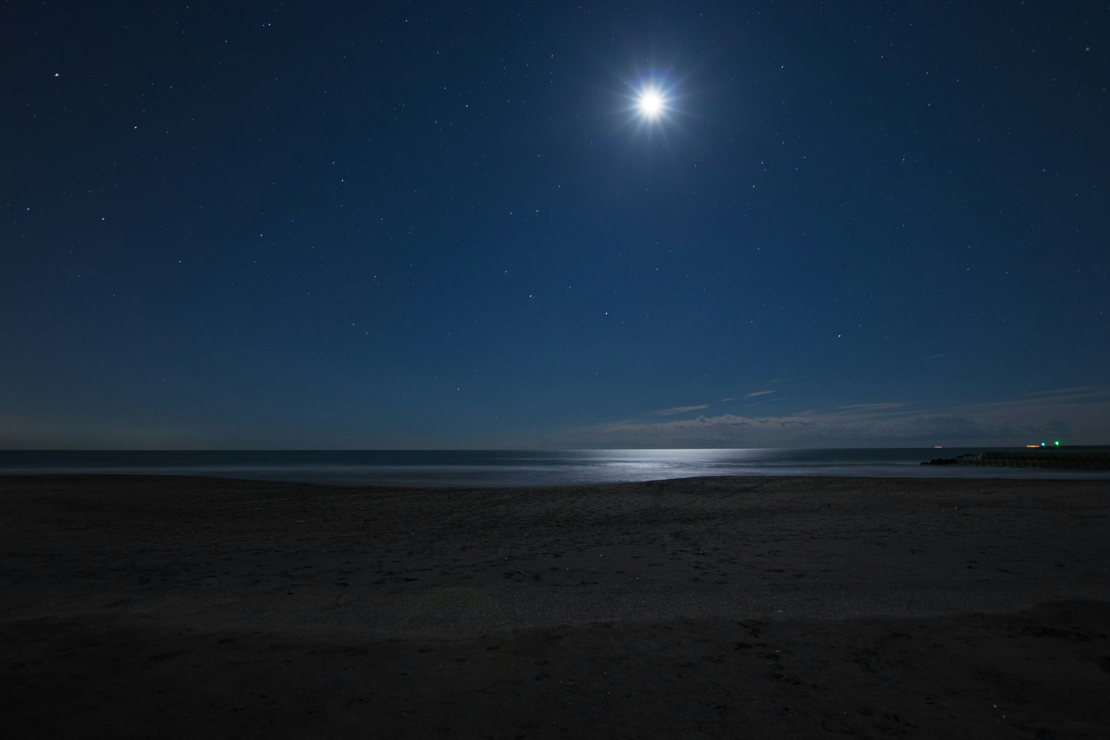 Scena costiera con una luna brillante e stelle nel cielo notturno