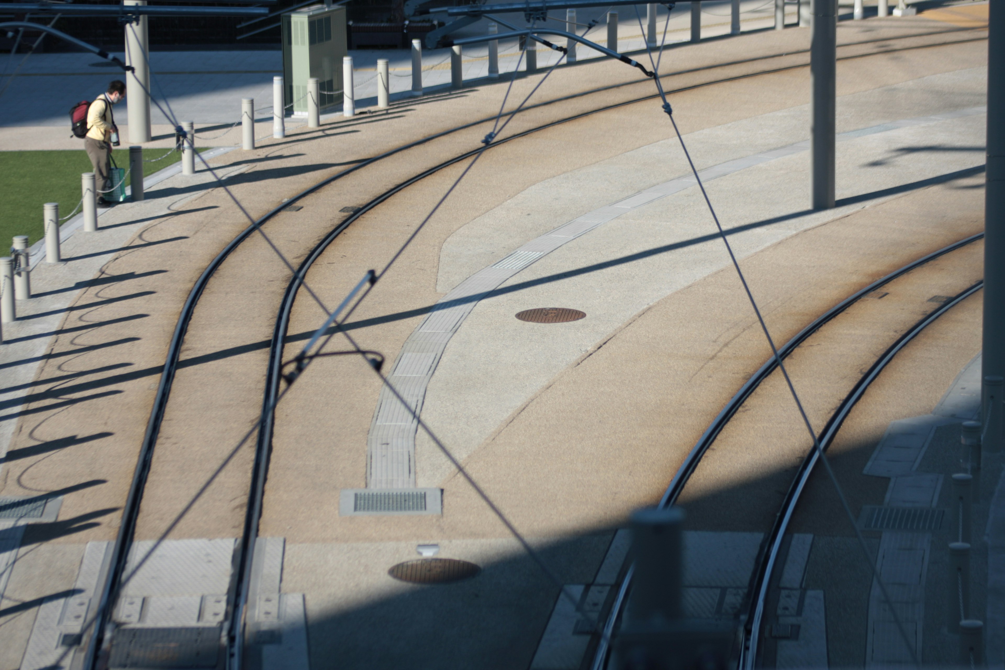 Tram tracks curving on a city street with a pedestrian nearby