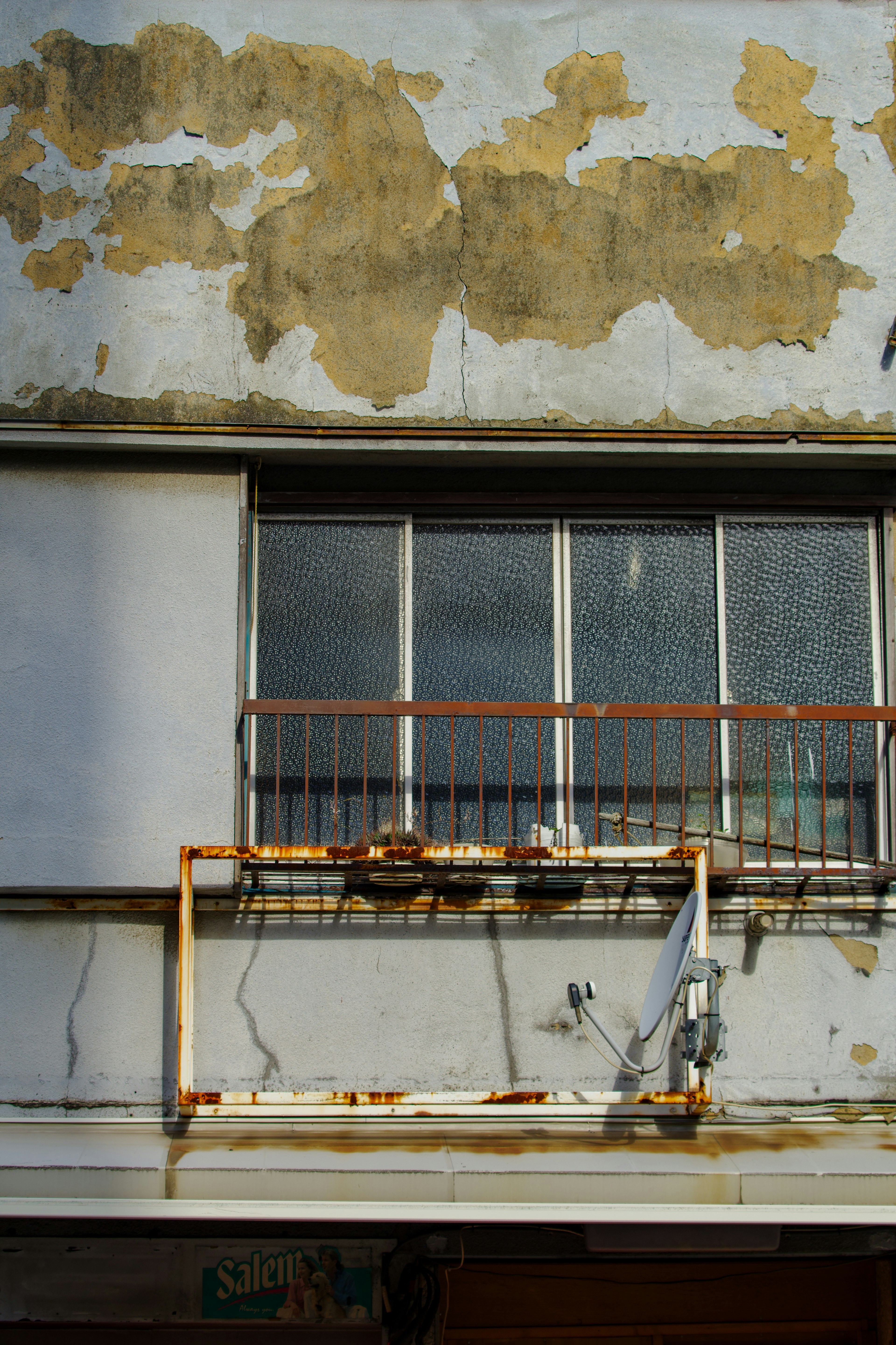 Façade d'immeuble vieillie avec peinture écaillée et rampe de balcon rouillée