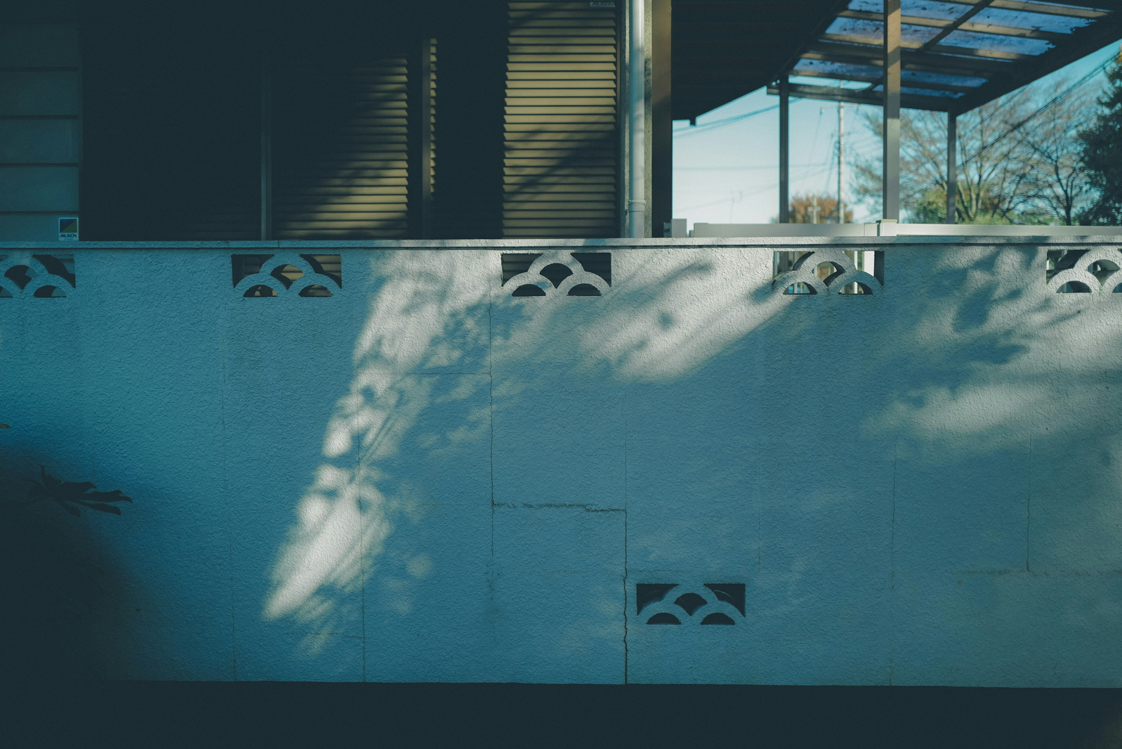 A blue wall with intricate patterns and shadows creating a serene atmosphere