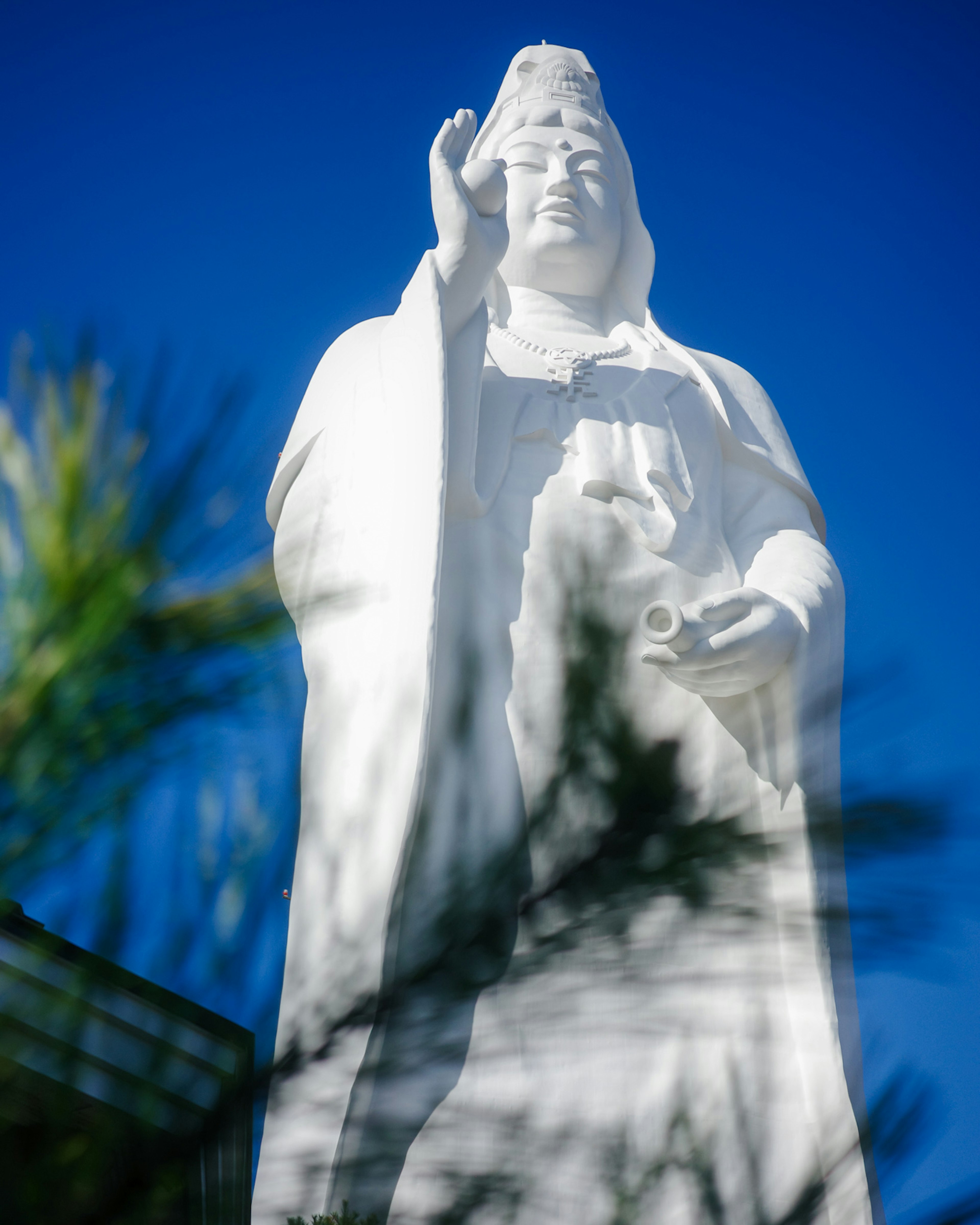 青空の下で立つ白い仏像の像