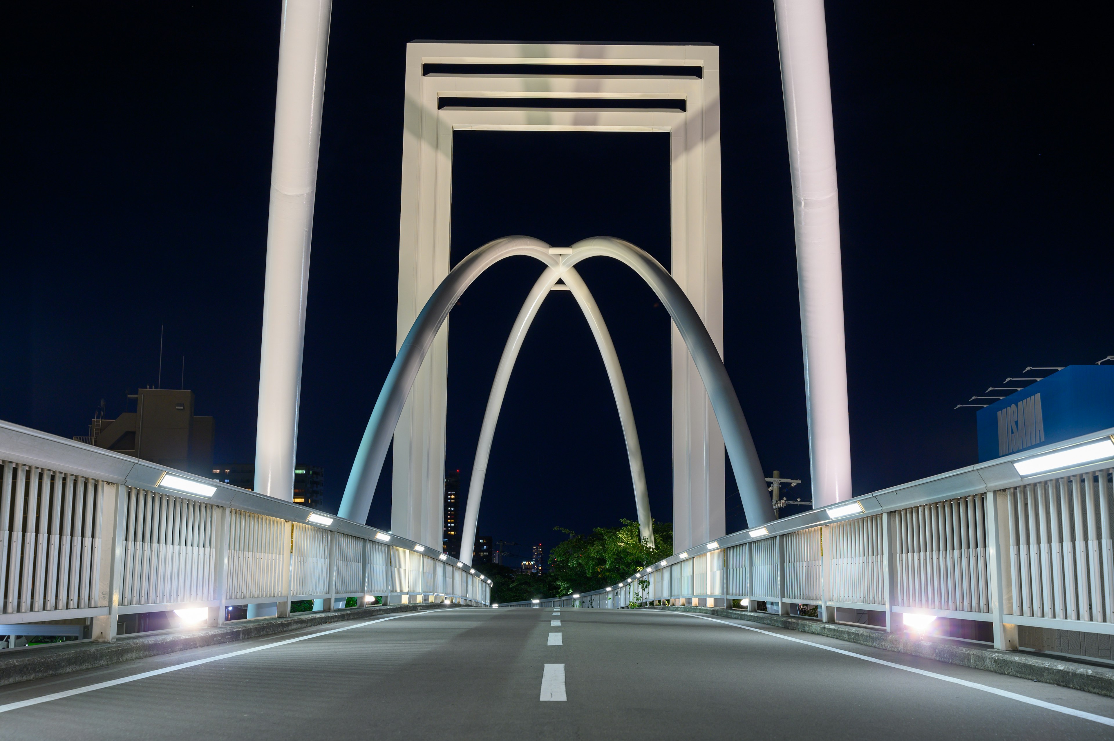 Foto de un puente de arco blanco por la noche en un entorno urbano