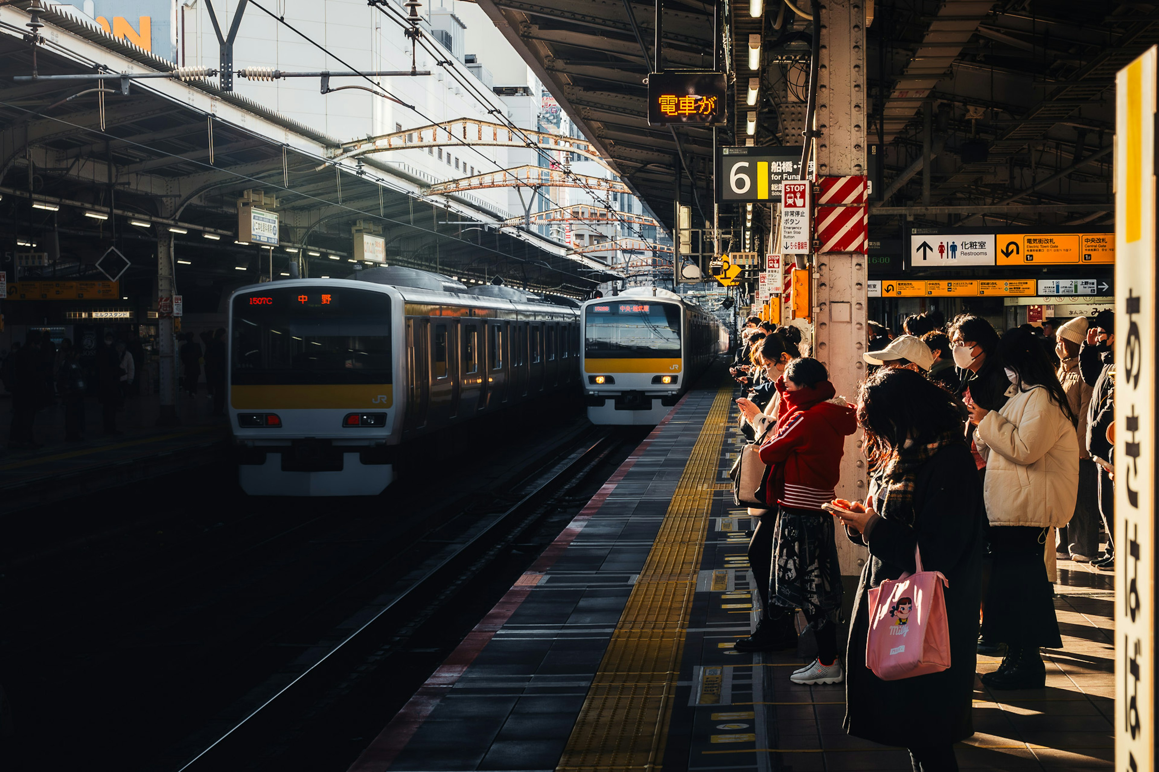 People waiting on a train platform with arriving trains