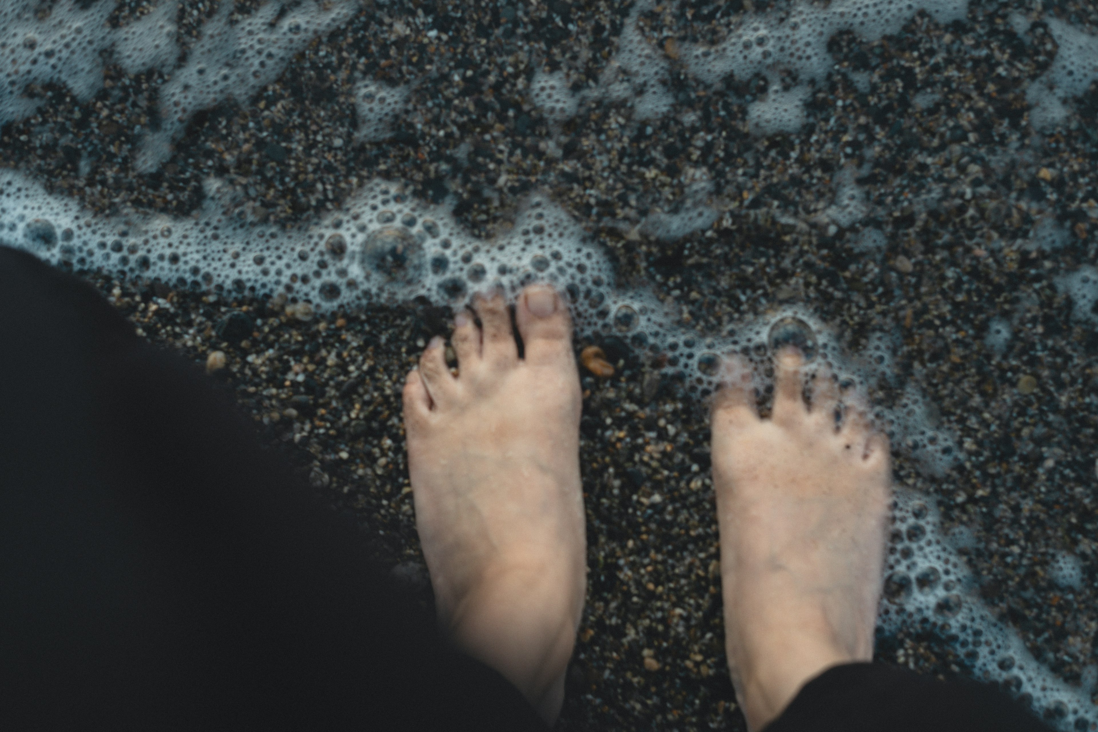 Pieds sur une plage de galets avec des vagues qui se brisent