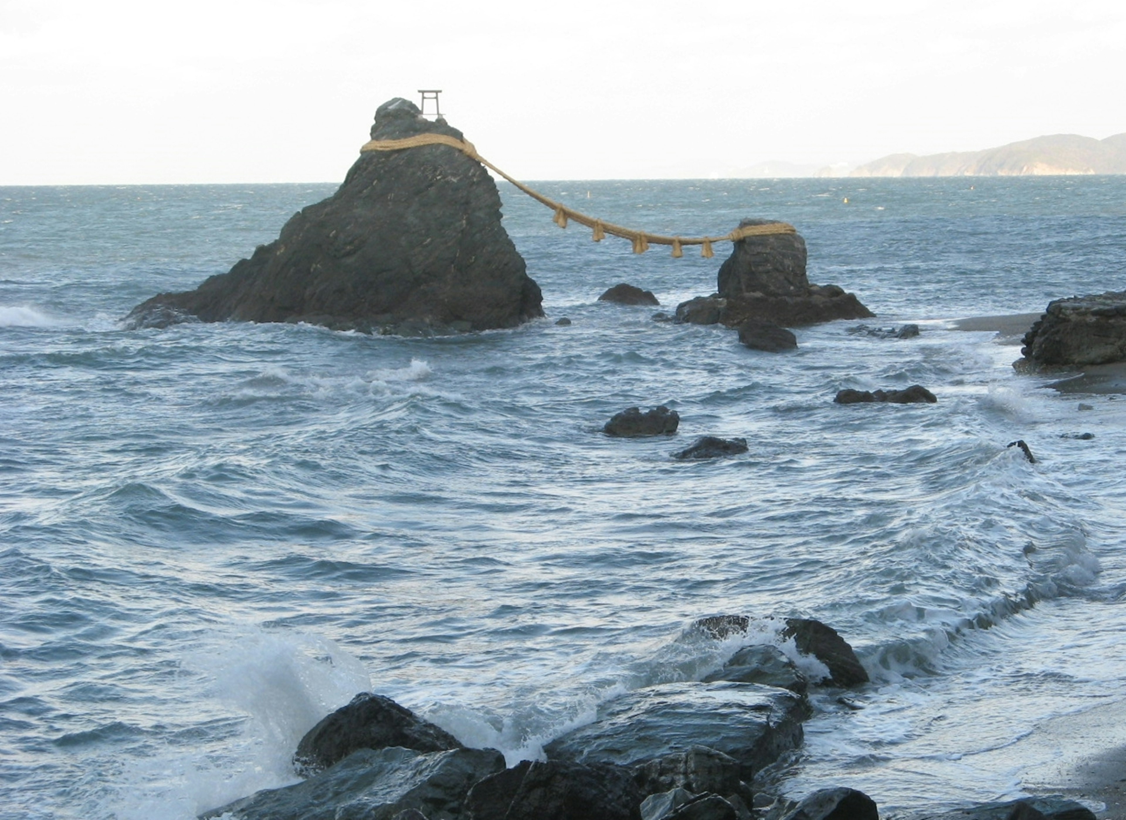 Vista costera con rocas y olas una estructura similar a un santuario en una roca