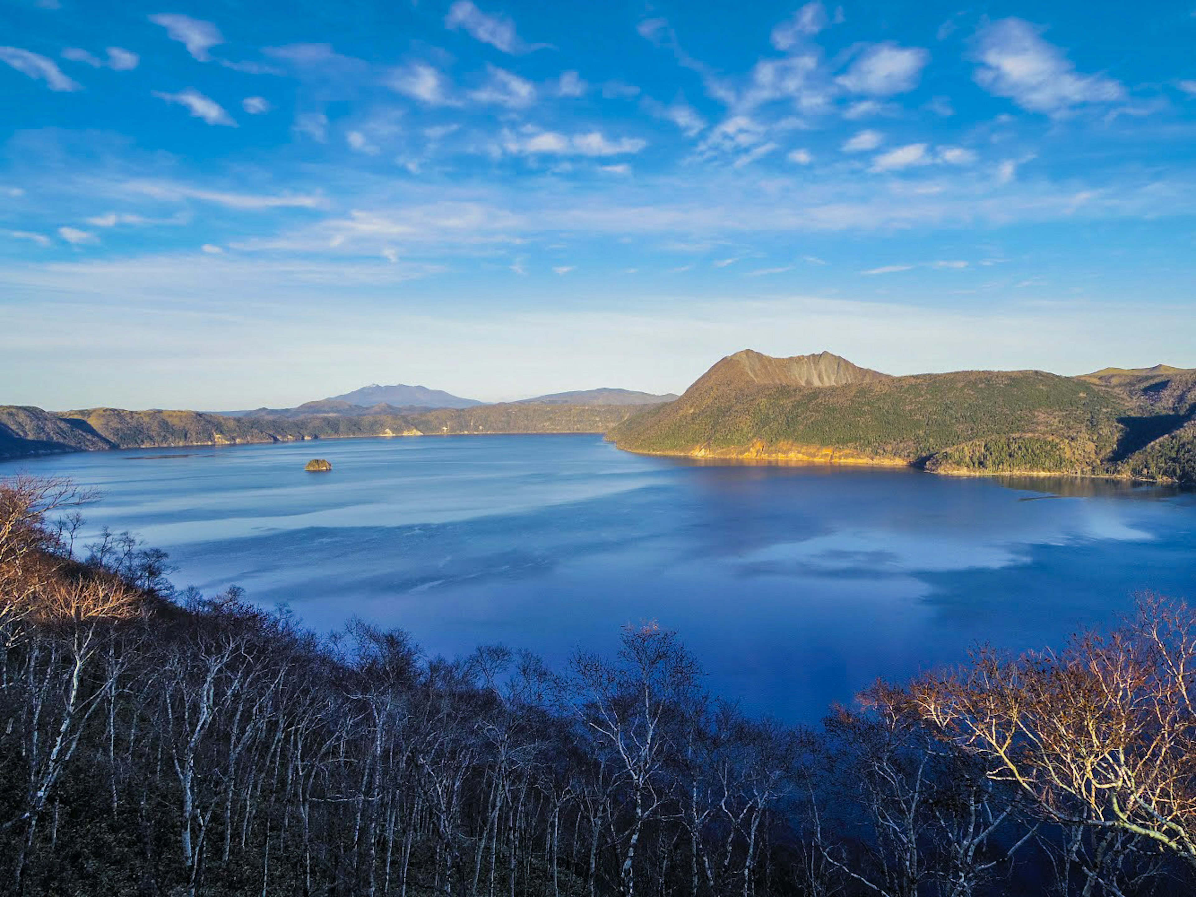 Vista panoramica di un lago circondato da montagne sotto un cielo blu