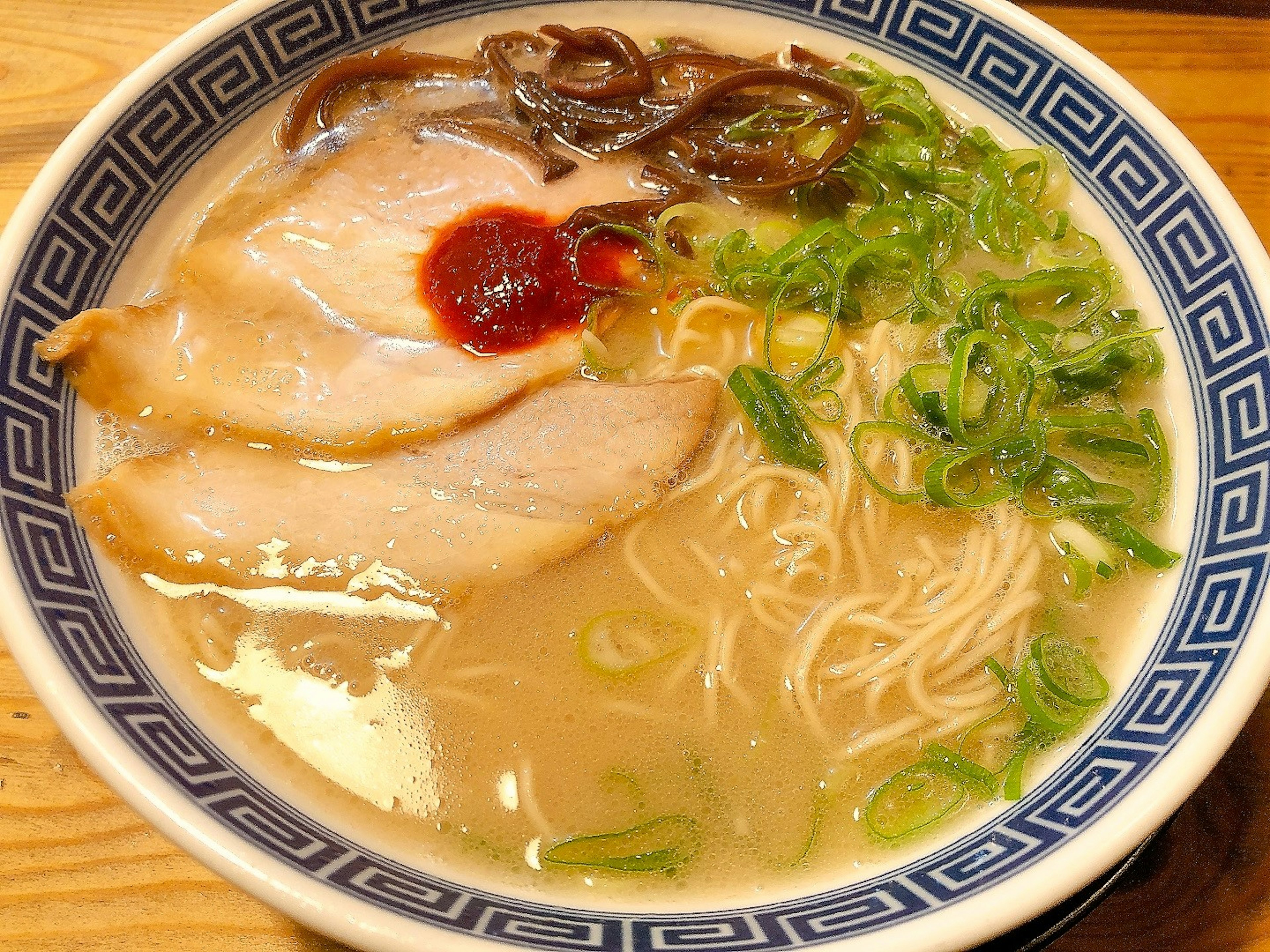 A bowl of tonkotsu ramen with slices of chashu and green onions