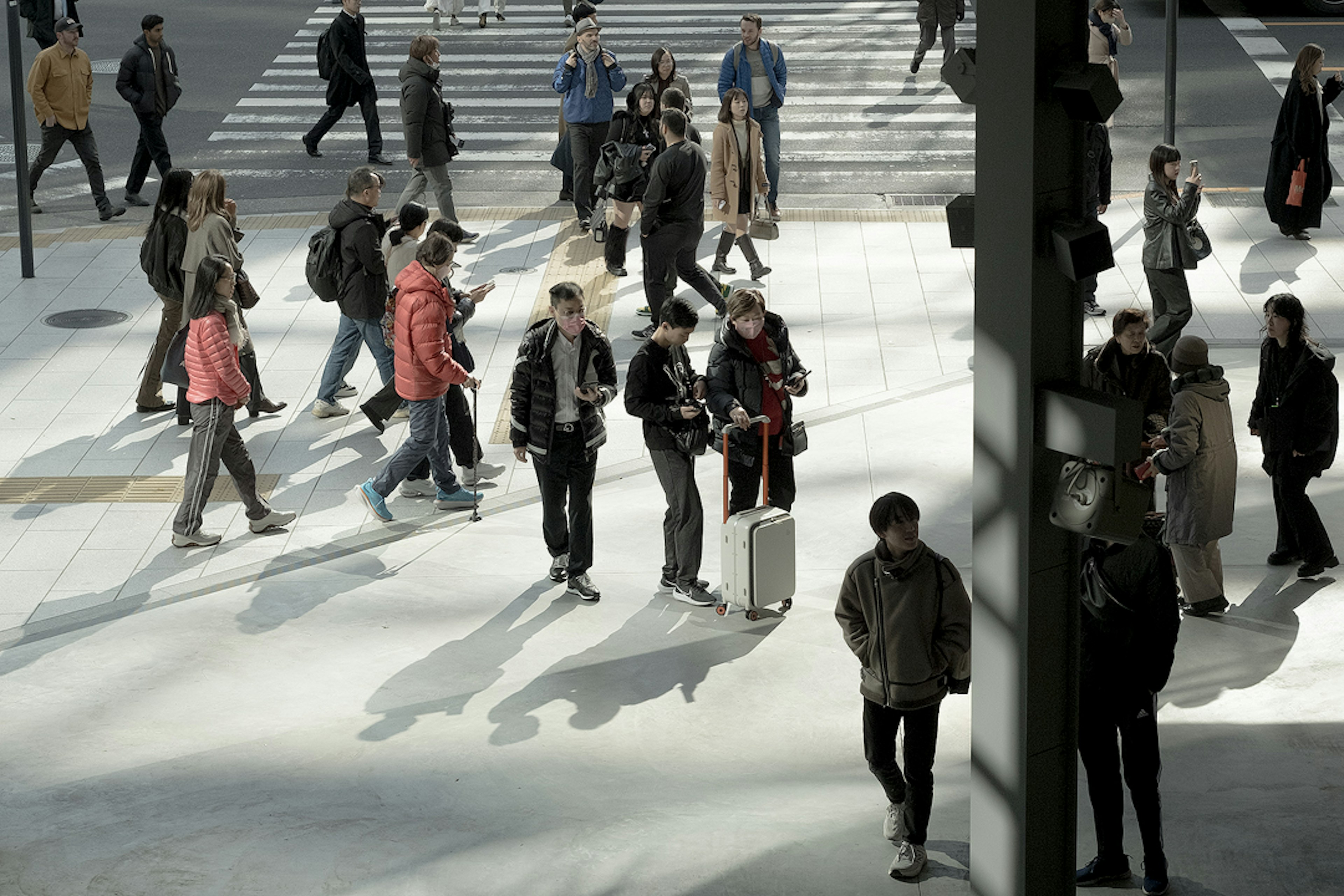 Foule de personnes traversant une intersection avec des ombres