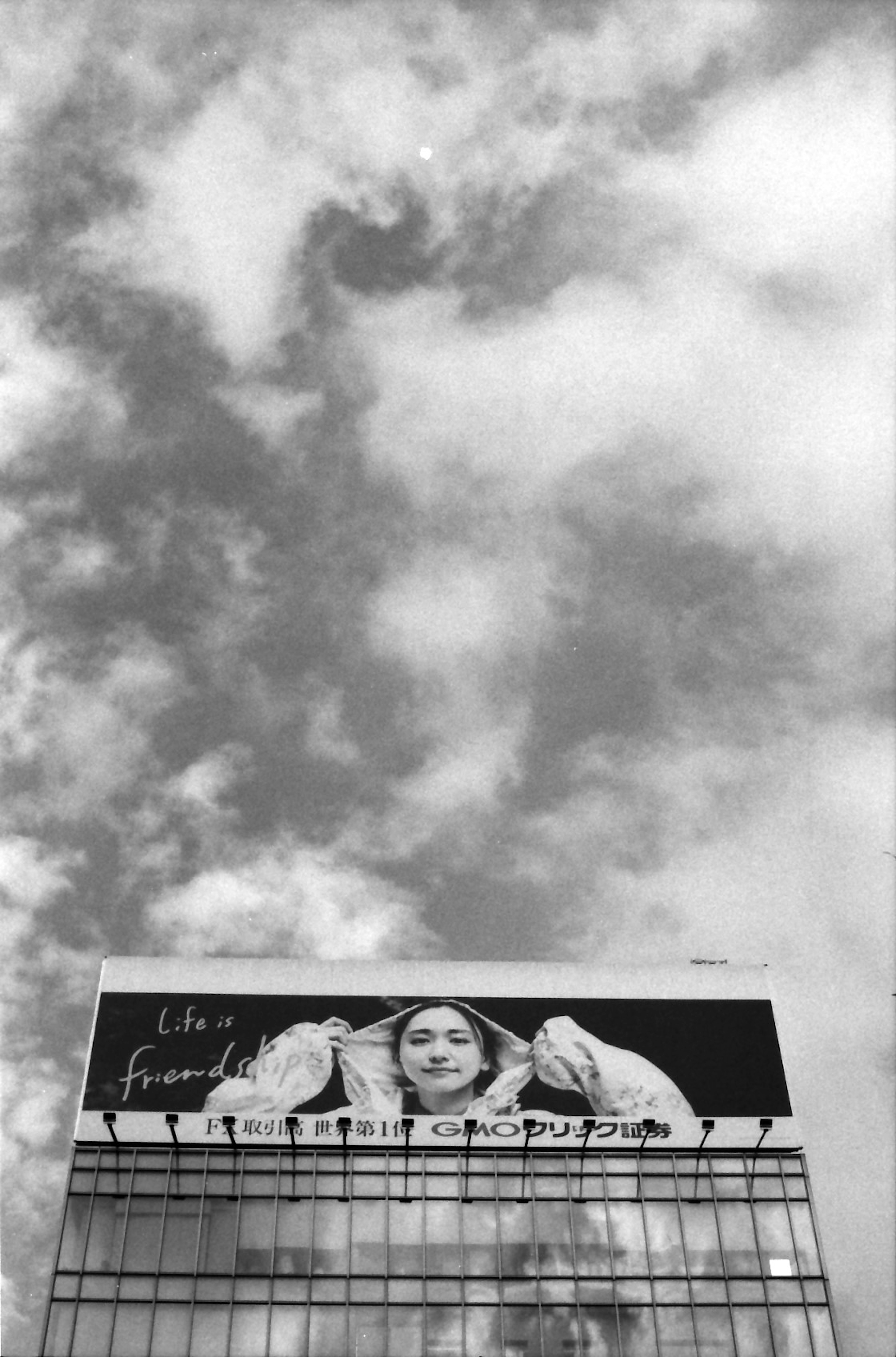 Murale in bianco e nero di una donna su un muro di un edificio con cielo nuvoloso