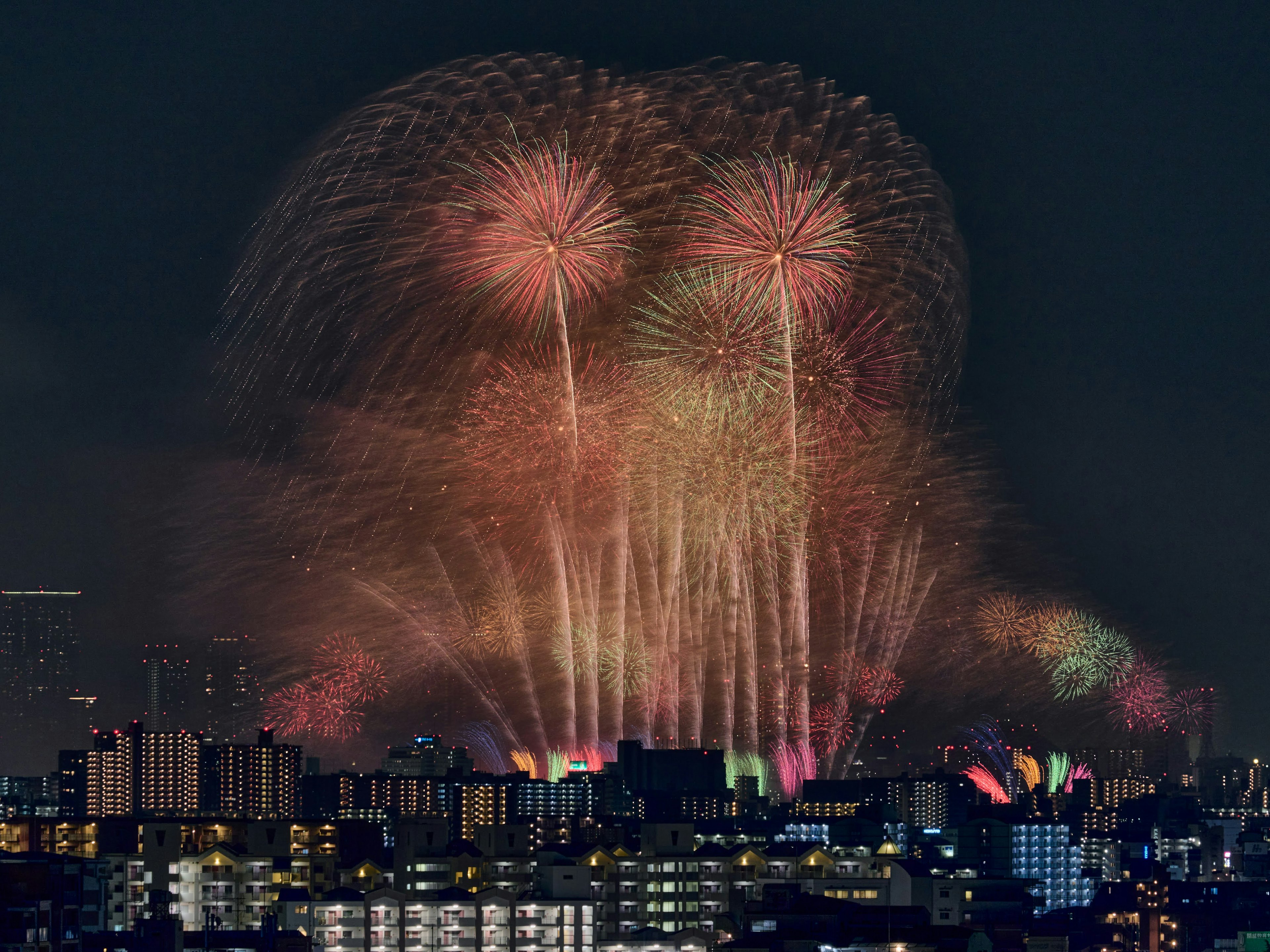 Fireworks illuminate the night sky over a city skyline