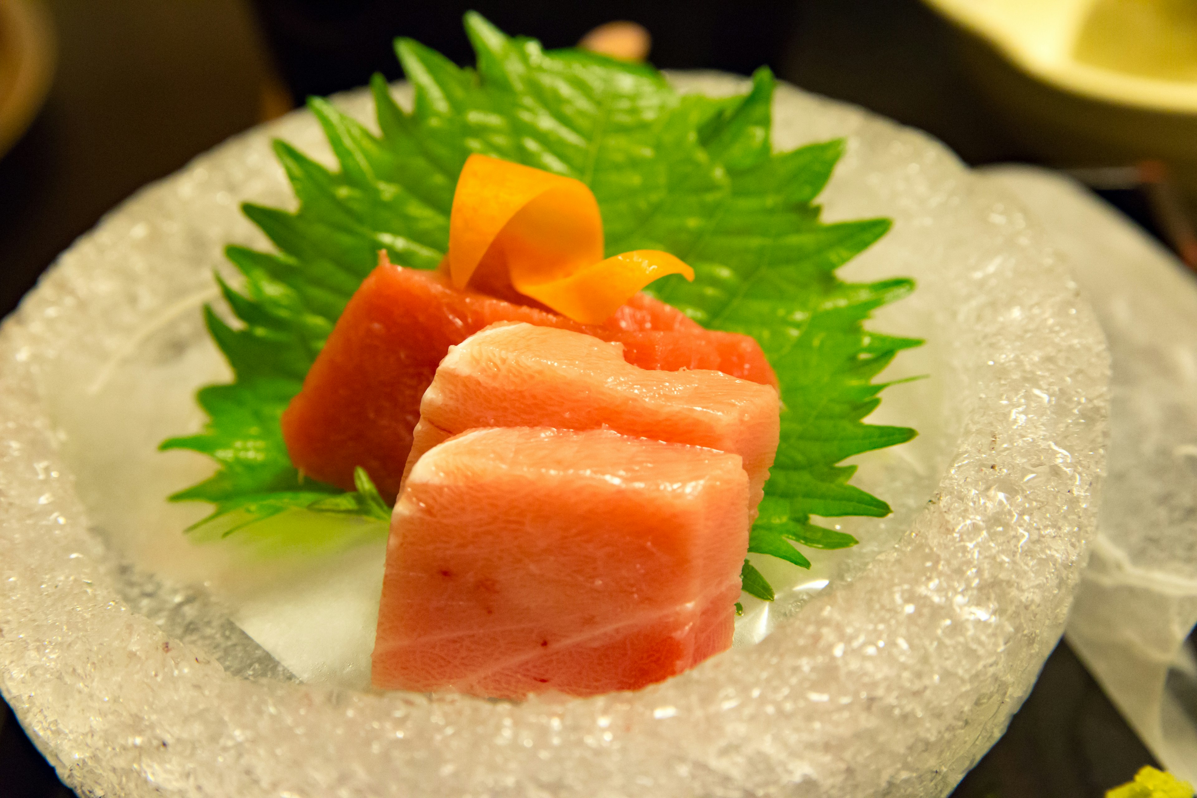 Fresh sashimi arranged on ice with green leaves