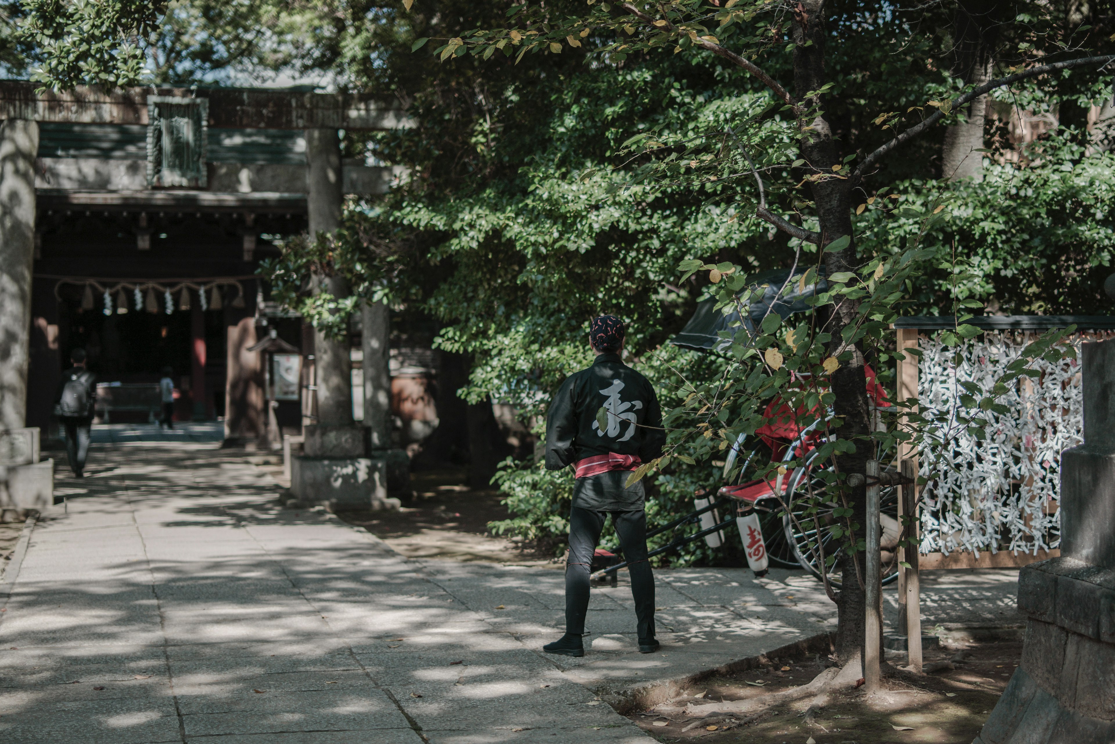 神社の前に立つ人と緑豊かな背景