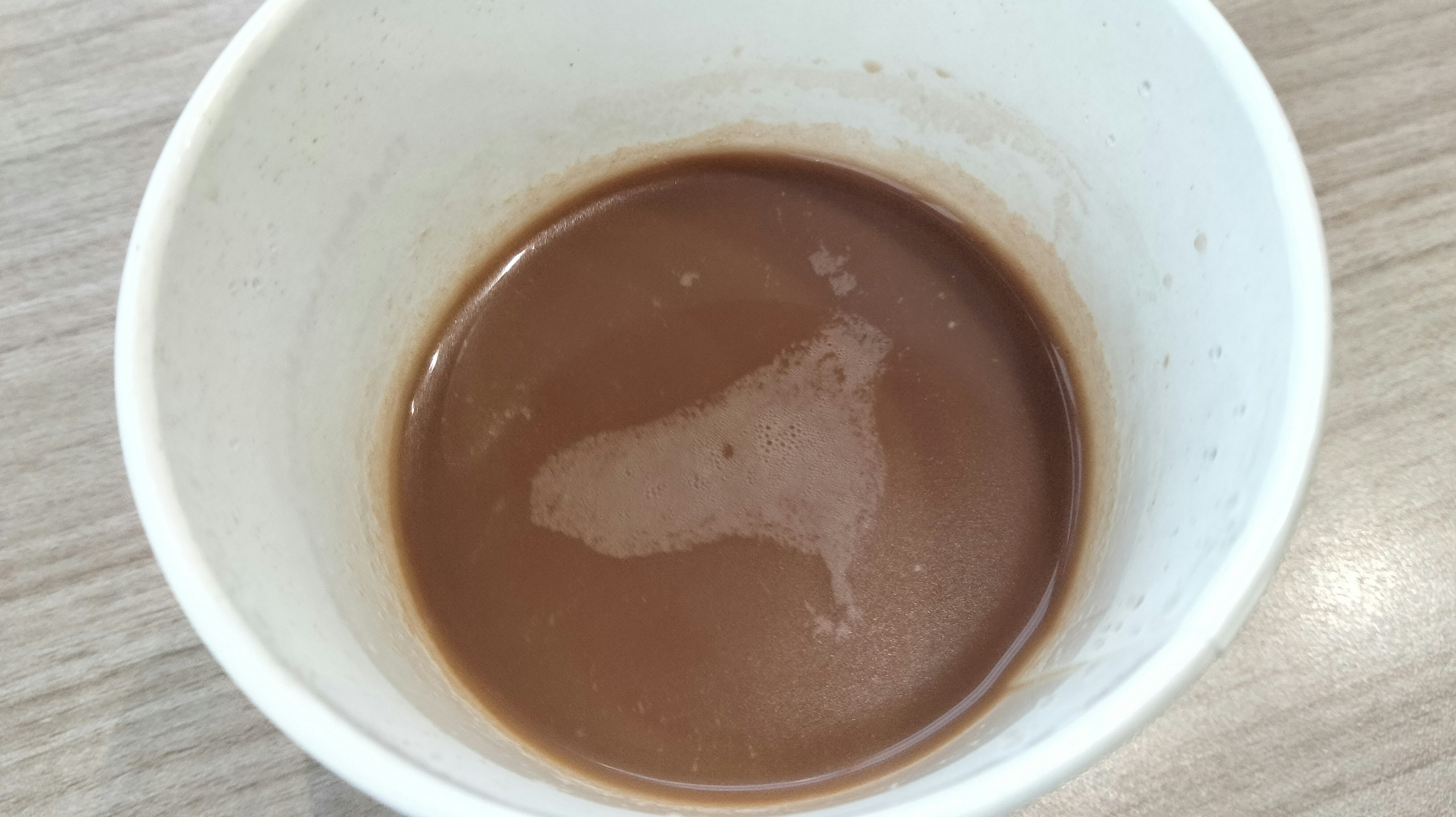 Top view of a white cup with brown liquid inside