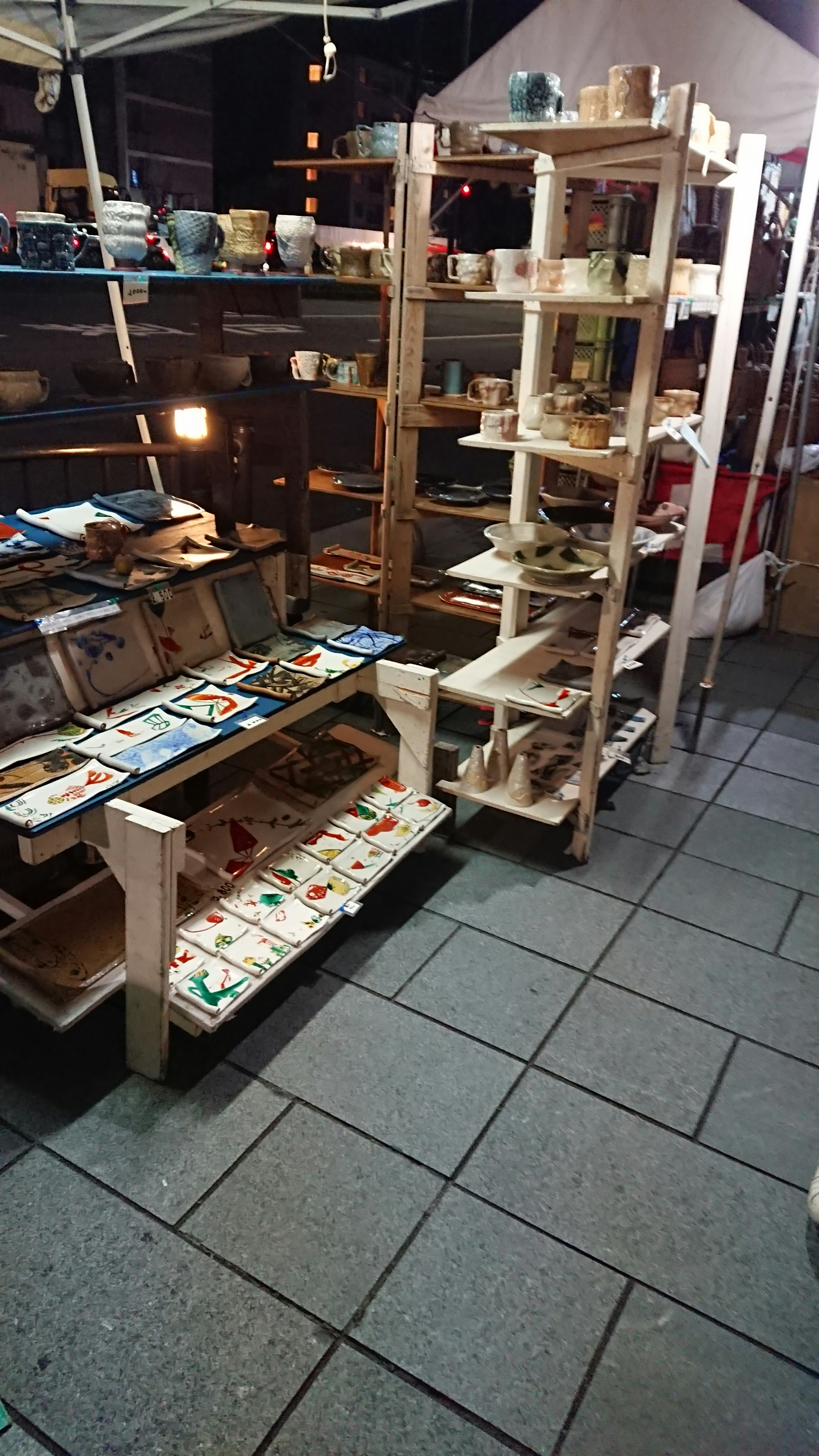 Market scene with wooden shelves displaying pottery and crafts