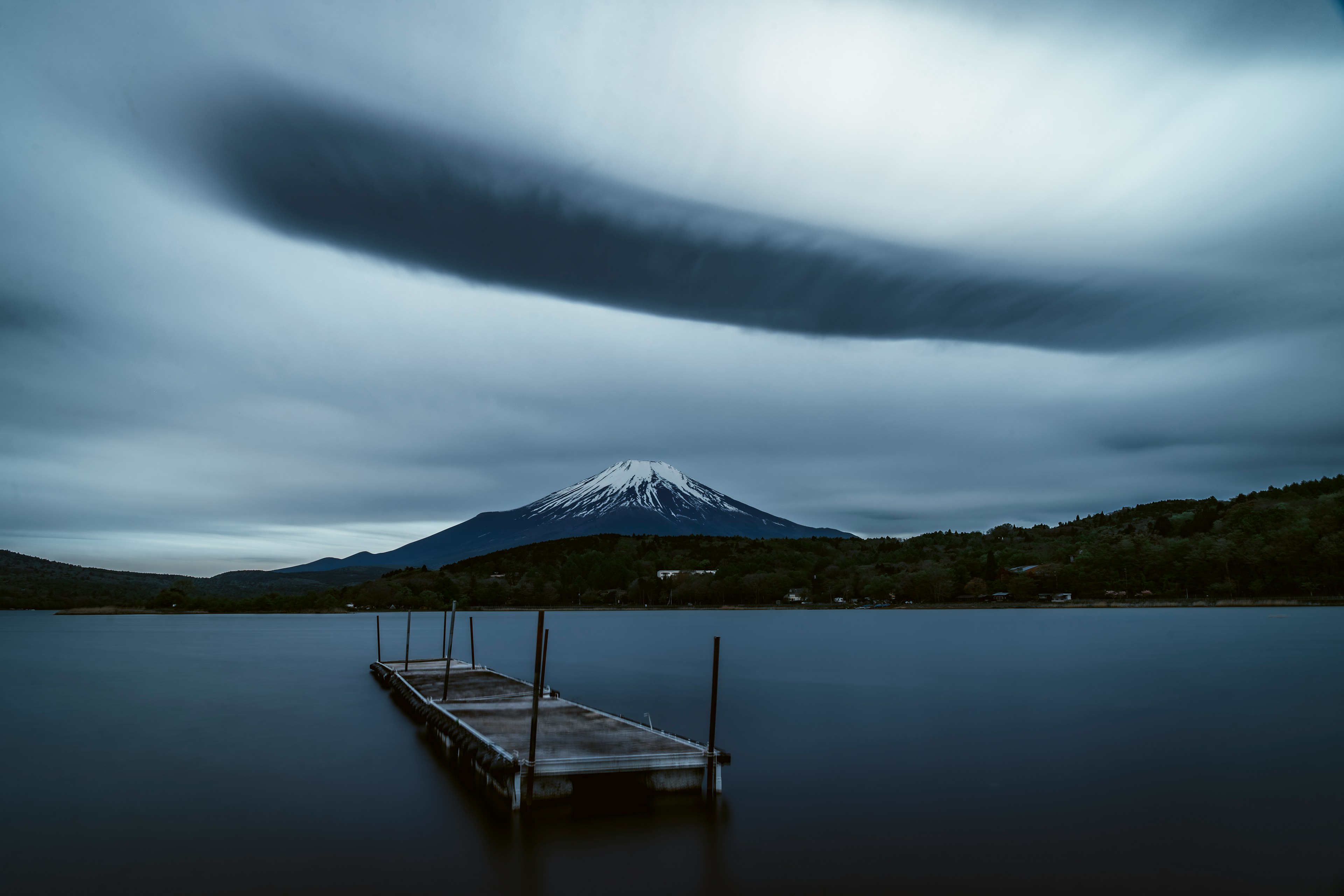 Vue panoramique du mont Fuji avec un lac calme nuages sombres dans le ciel et un quai en bois