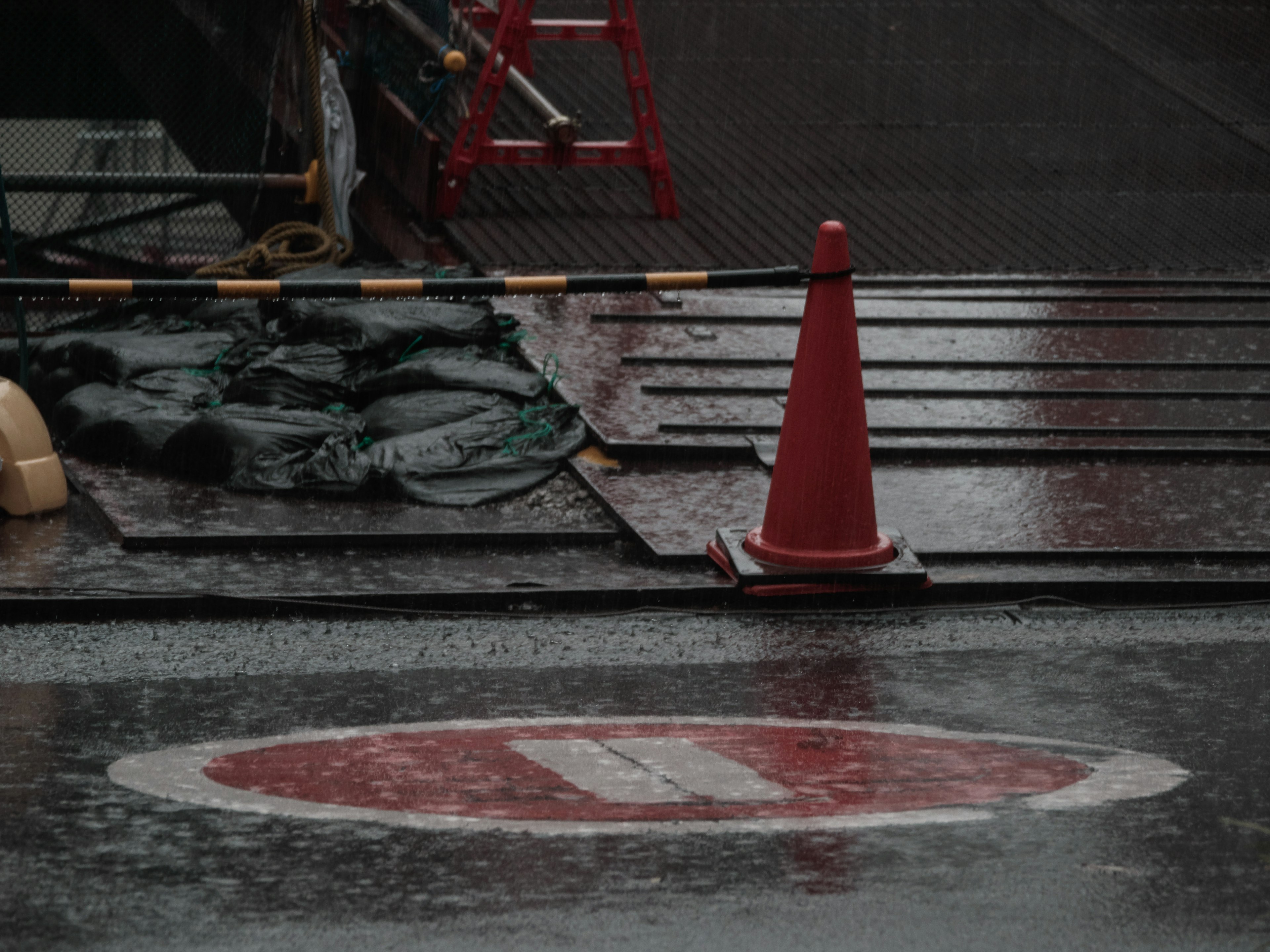 Cône de circulation rouge à côté d'un panneau d'interdiction sur une surface mouillée