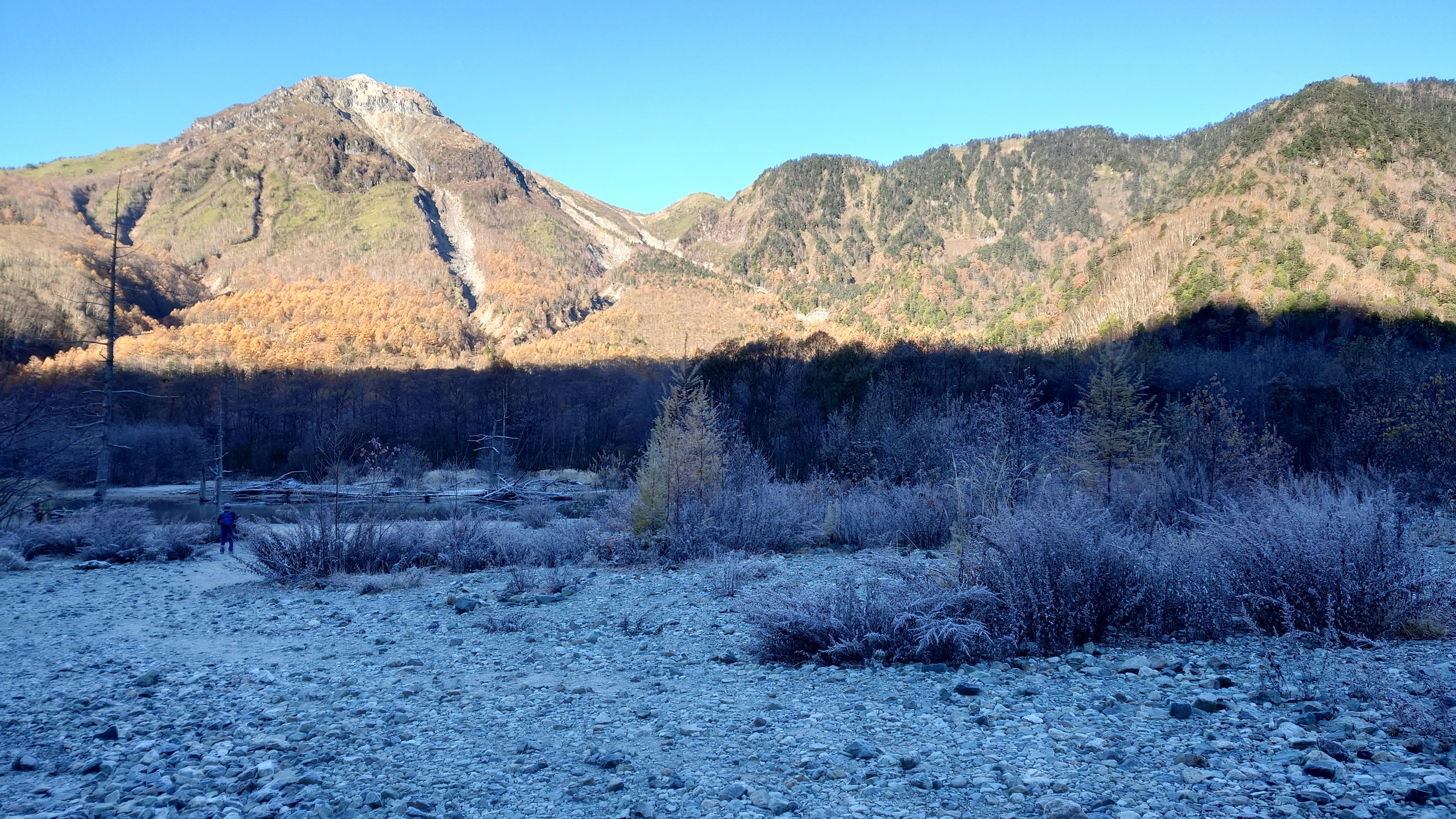 Frostige Landschaft mit gefrorenem Fluss und Bergen im Hintergrund