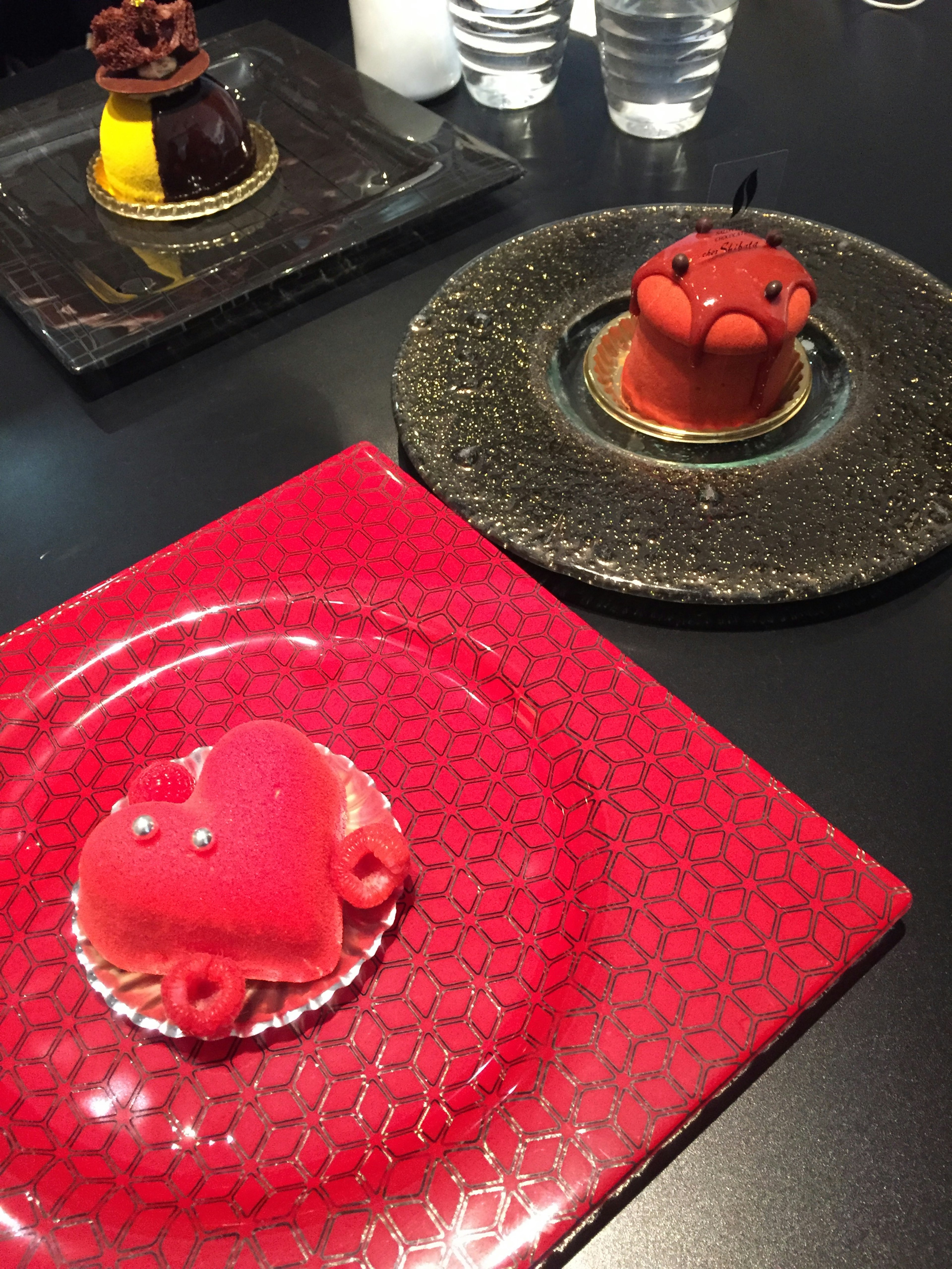 Red heart-shaped dessert and bear-shaped dessert on a black plate