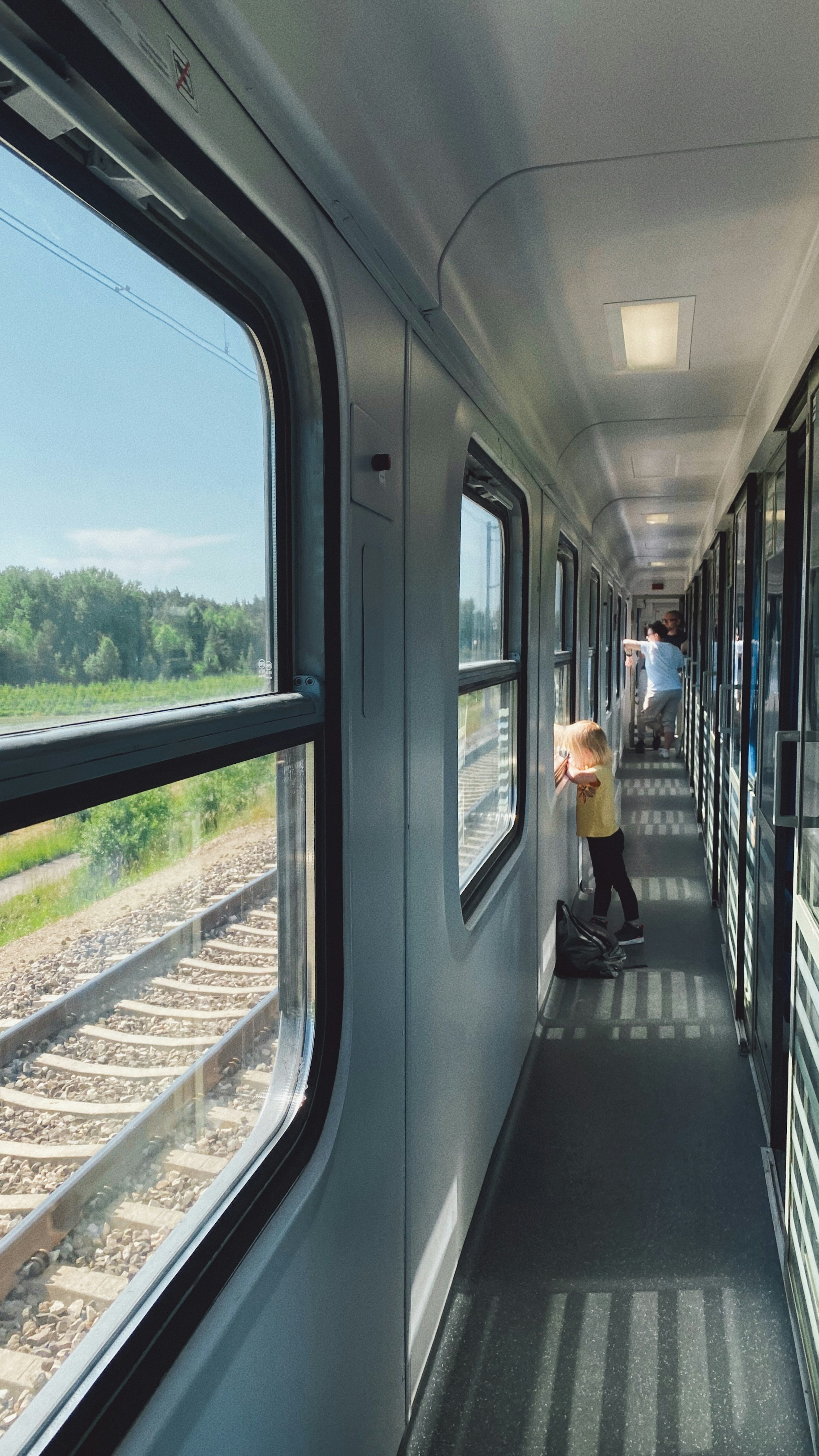 ภายในทางเดินของรถไฟมีเด็กและผู้ใหญ่กำลังมองออกนอกหน้าต่าง