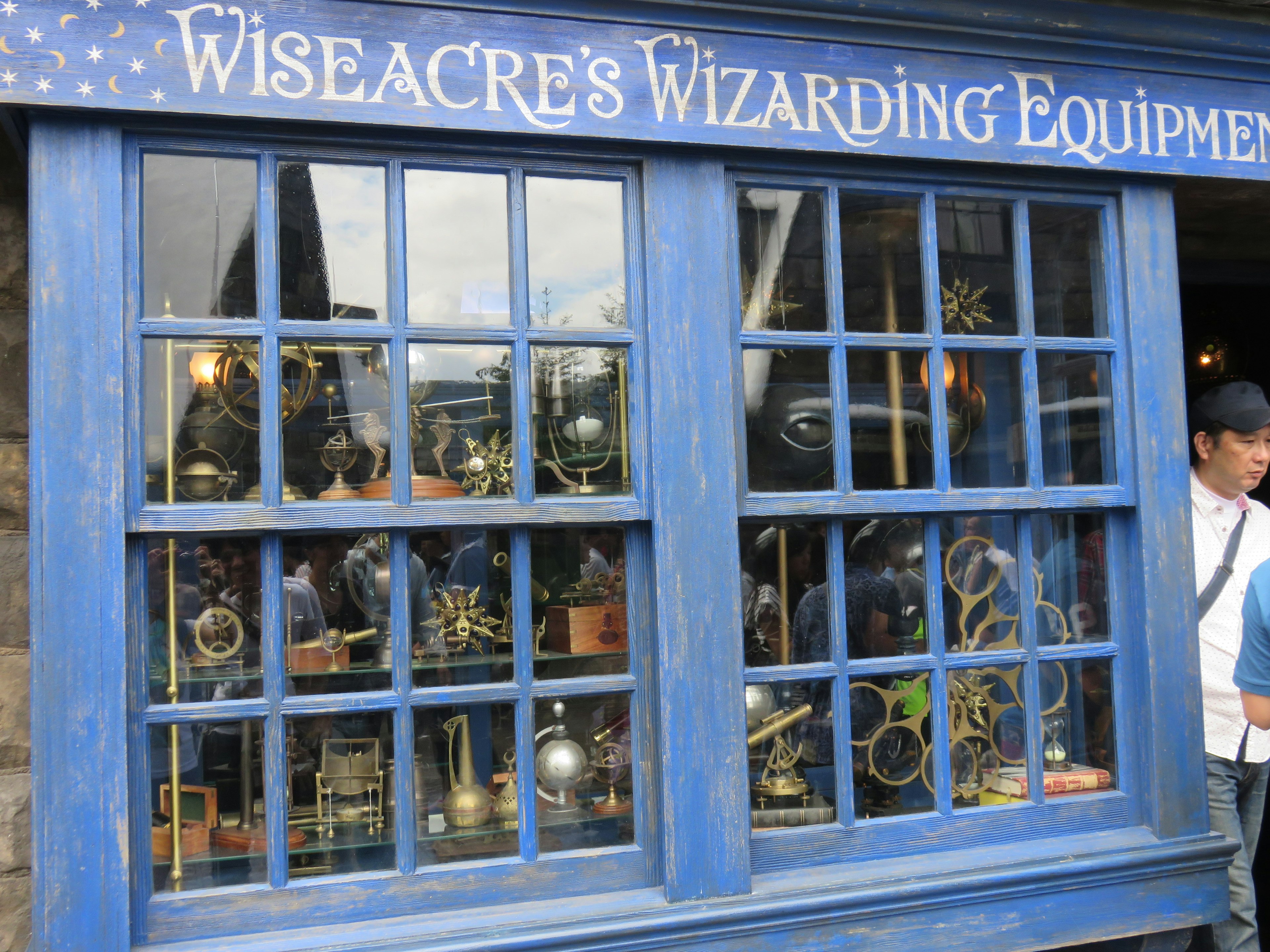 Vista exterior de Wiseacre's Wizarding Equipment con ventana azul y objetos exhibidos