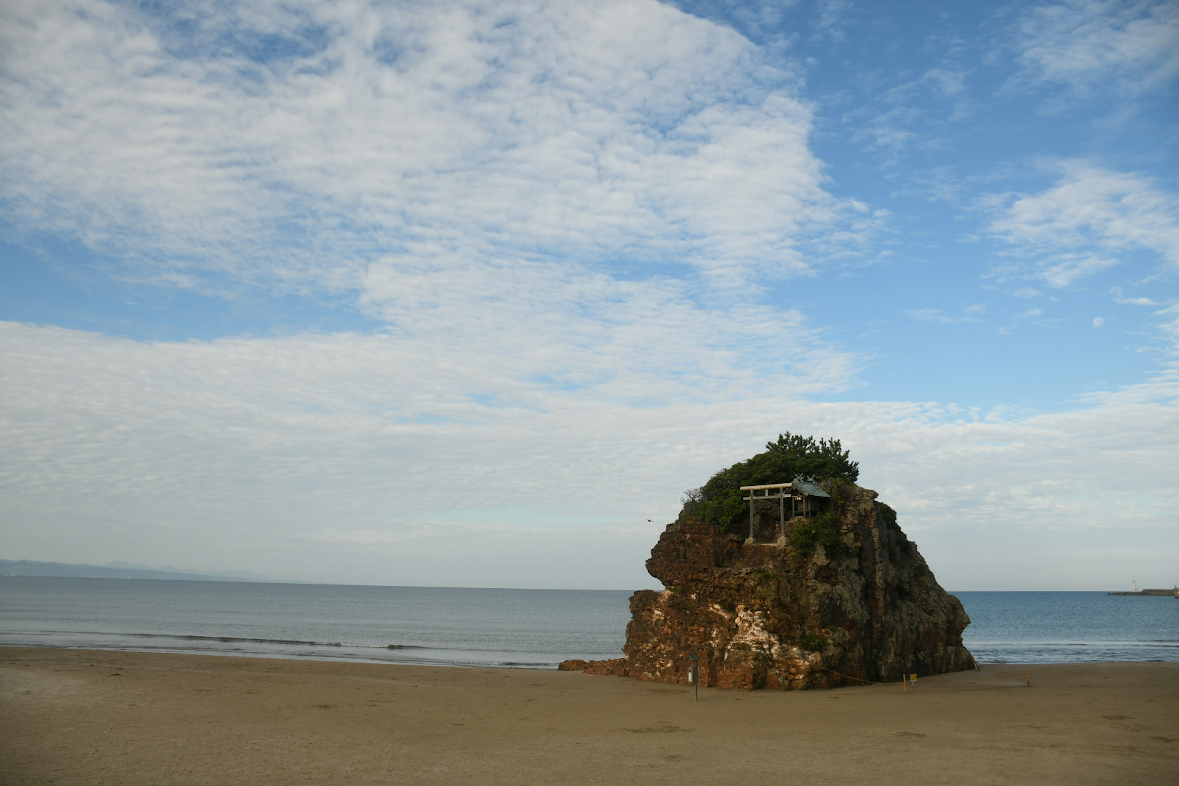 Ein Felsen an einem ruhigen Strand unter einem blauen Himmel