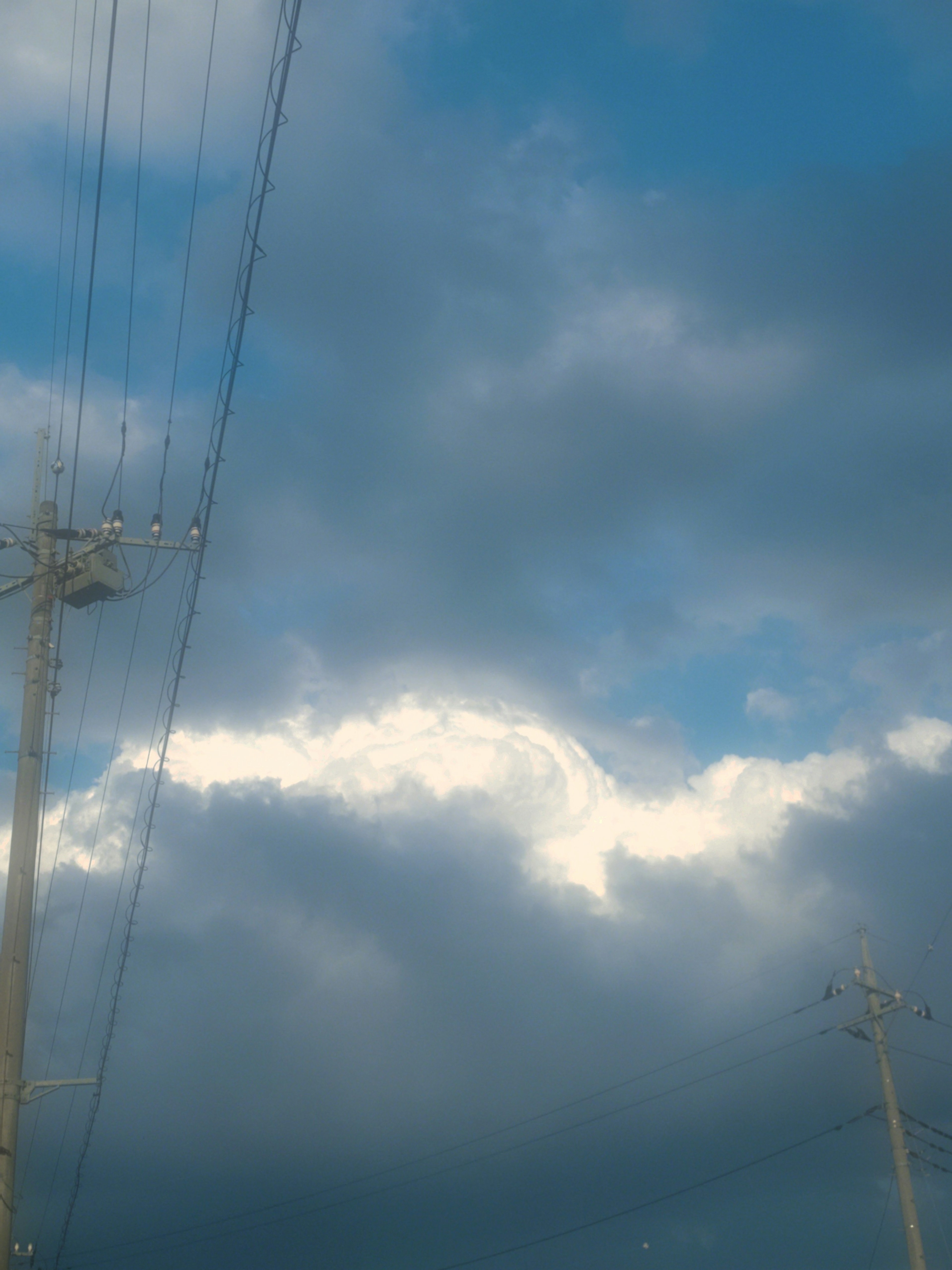 Un paysage avec un ciel bleu, des nuages blancs et des lignes électriques